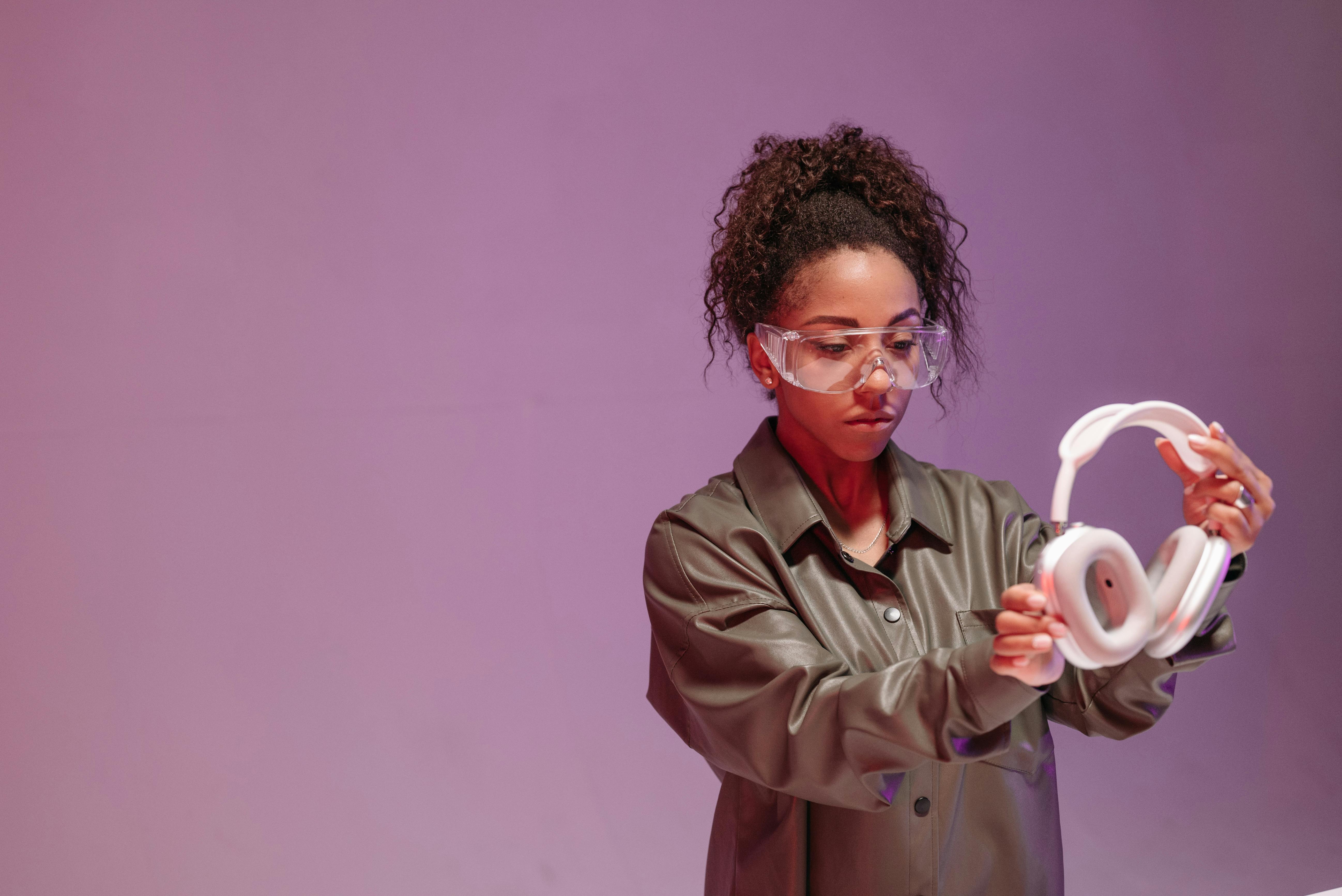 A Woman Wearing a Goggles in Gray Jacket Holding a Headphone