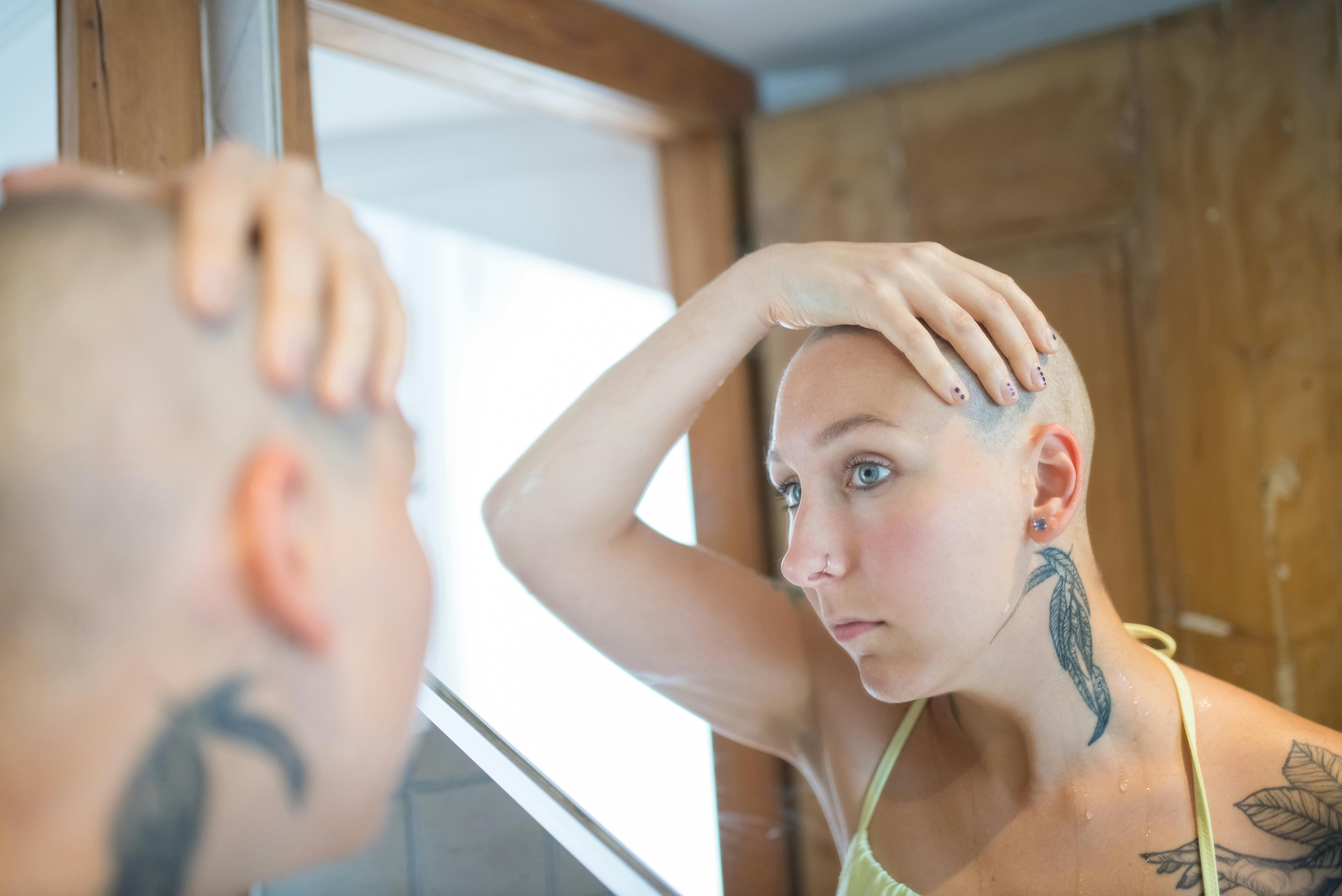 A Woman with Bald Head Looking at the Mirror