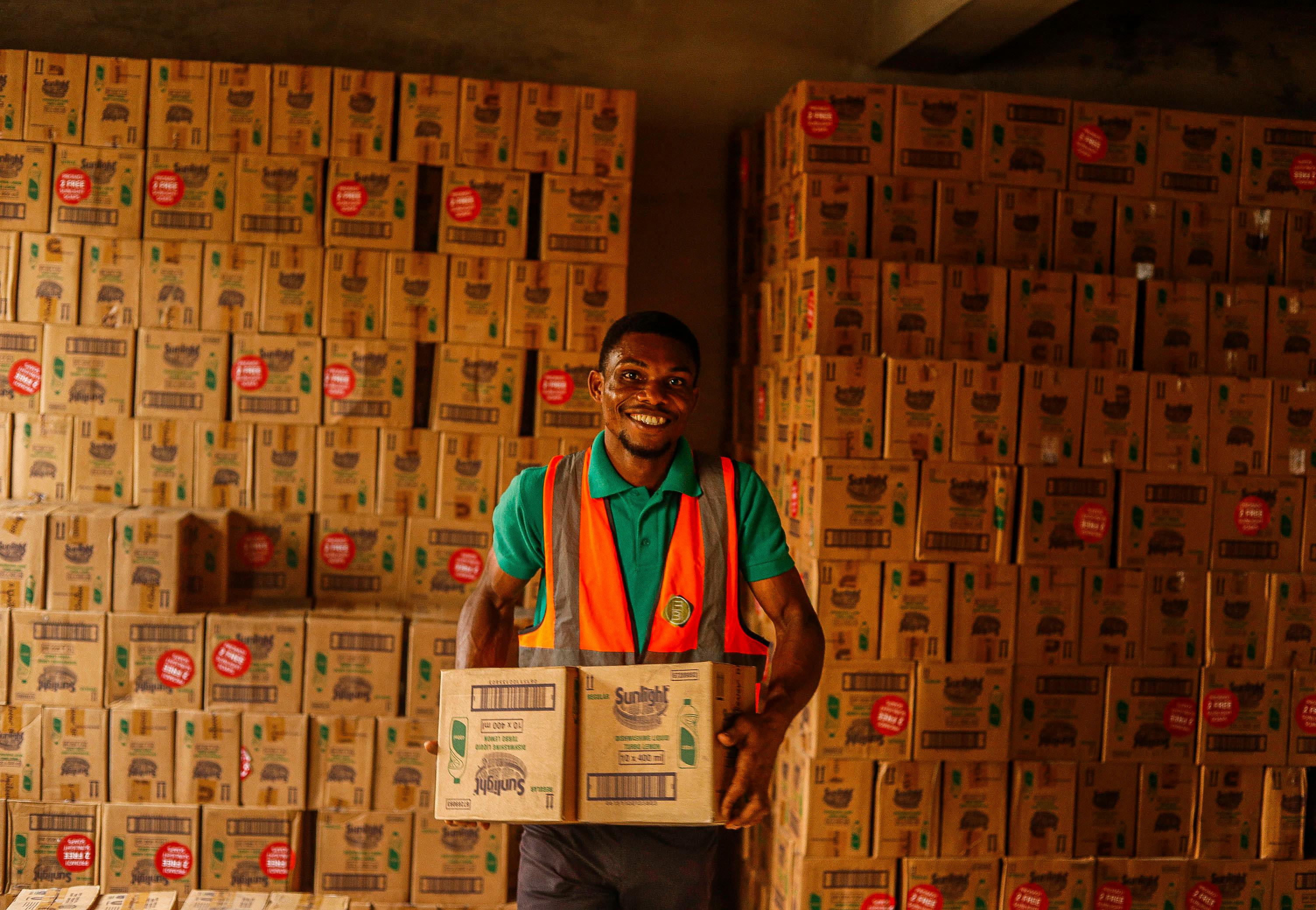 Smiling Man Working in a Warehouse Holding Boxes