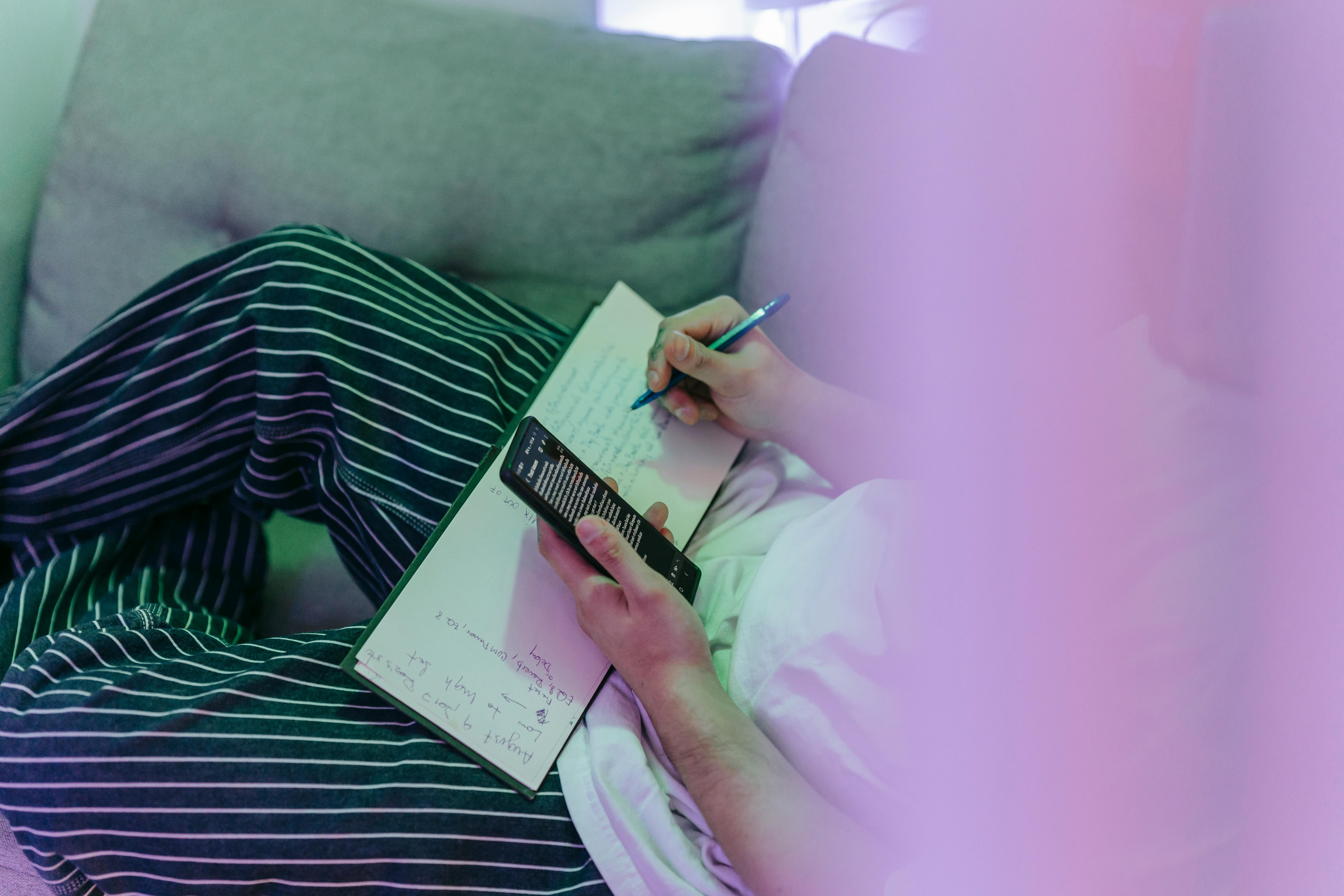 Person Writing in Notebook using Smart Phone