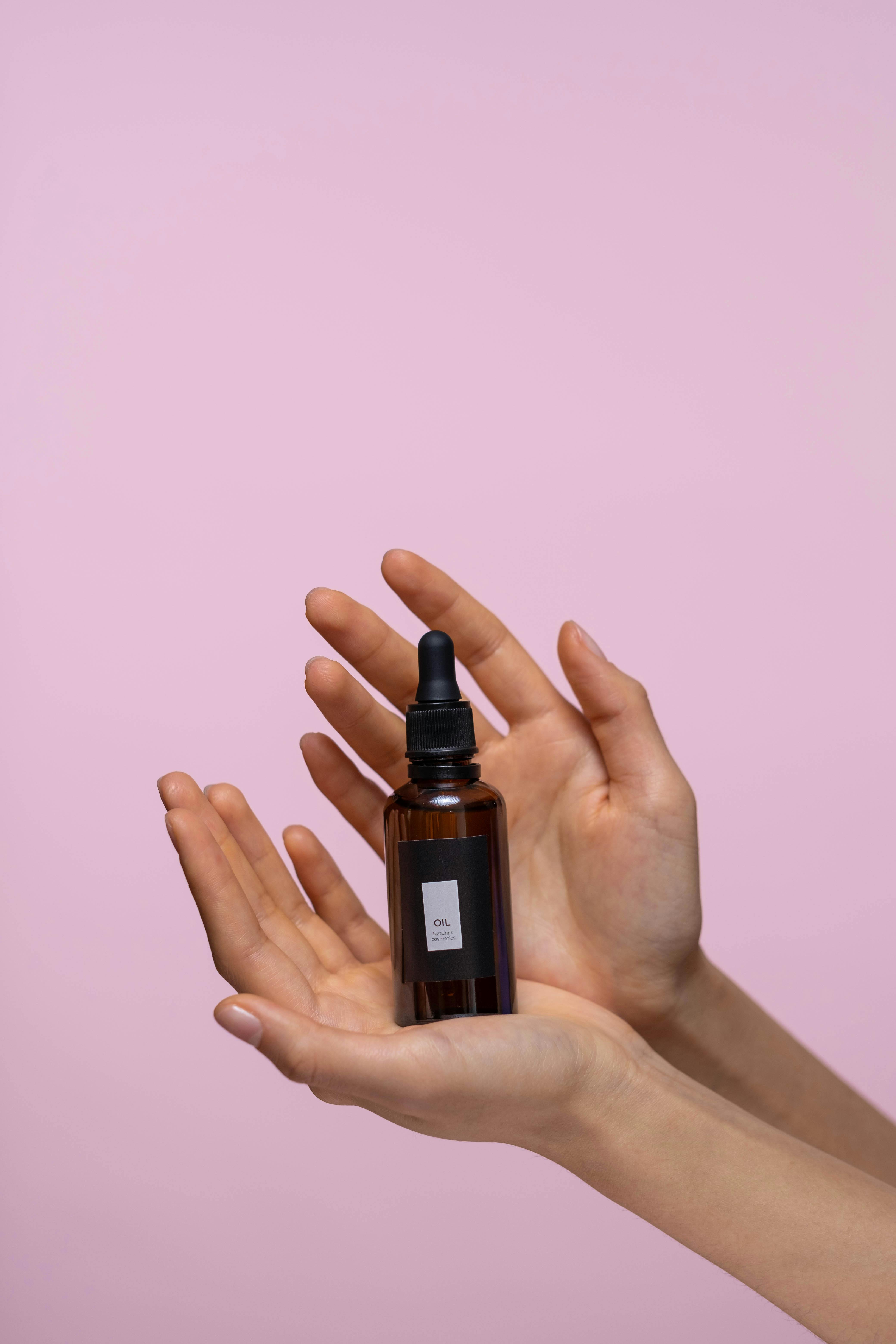 Person Holding A Bottle Of Serum