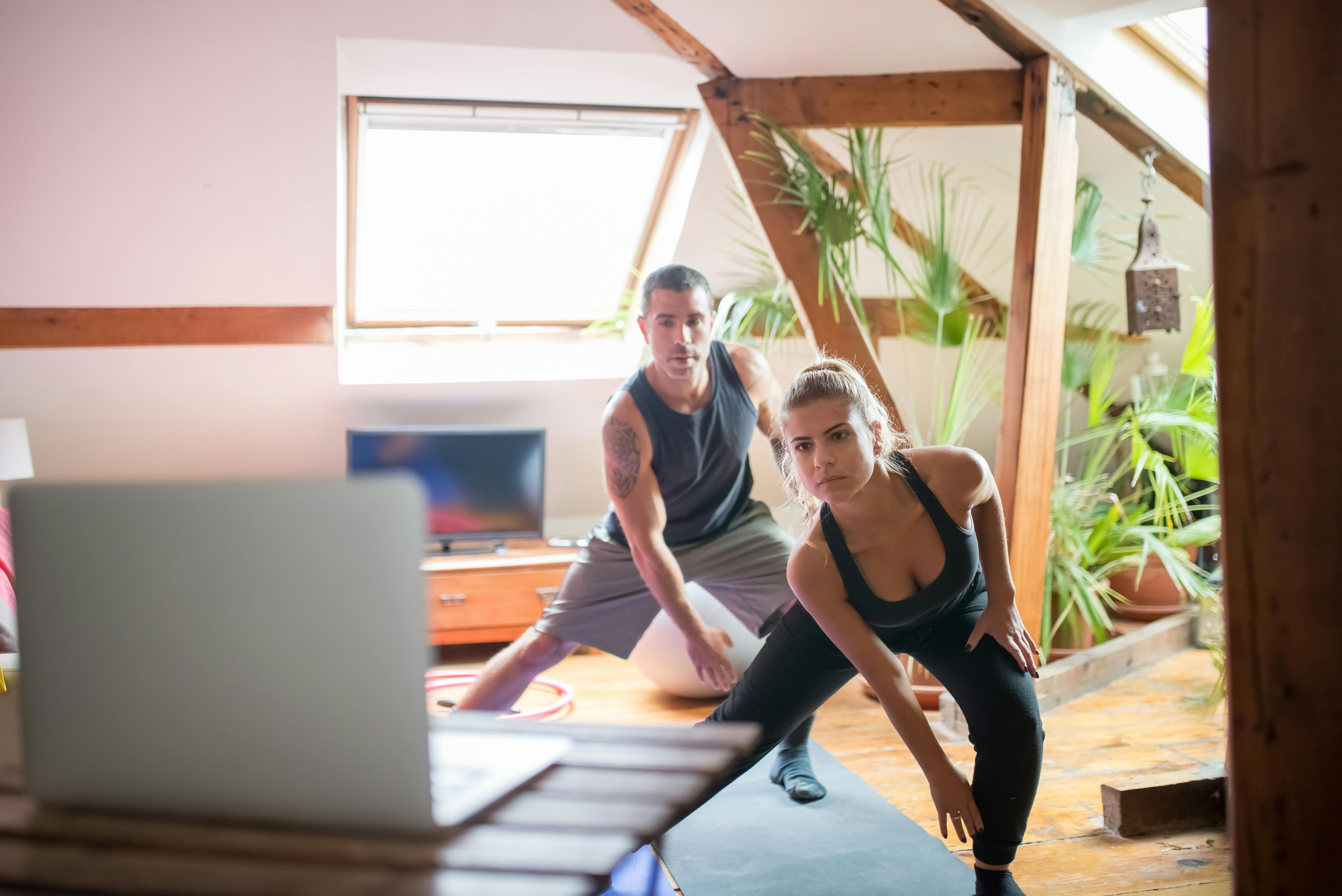 Man and Woman Watching on a Laptop While Working Out