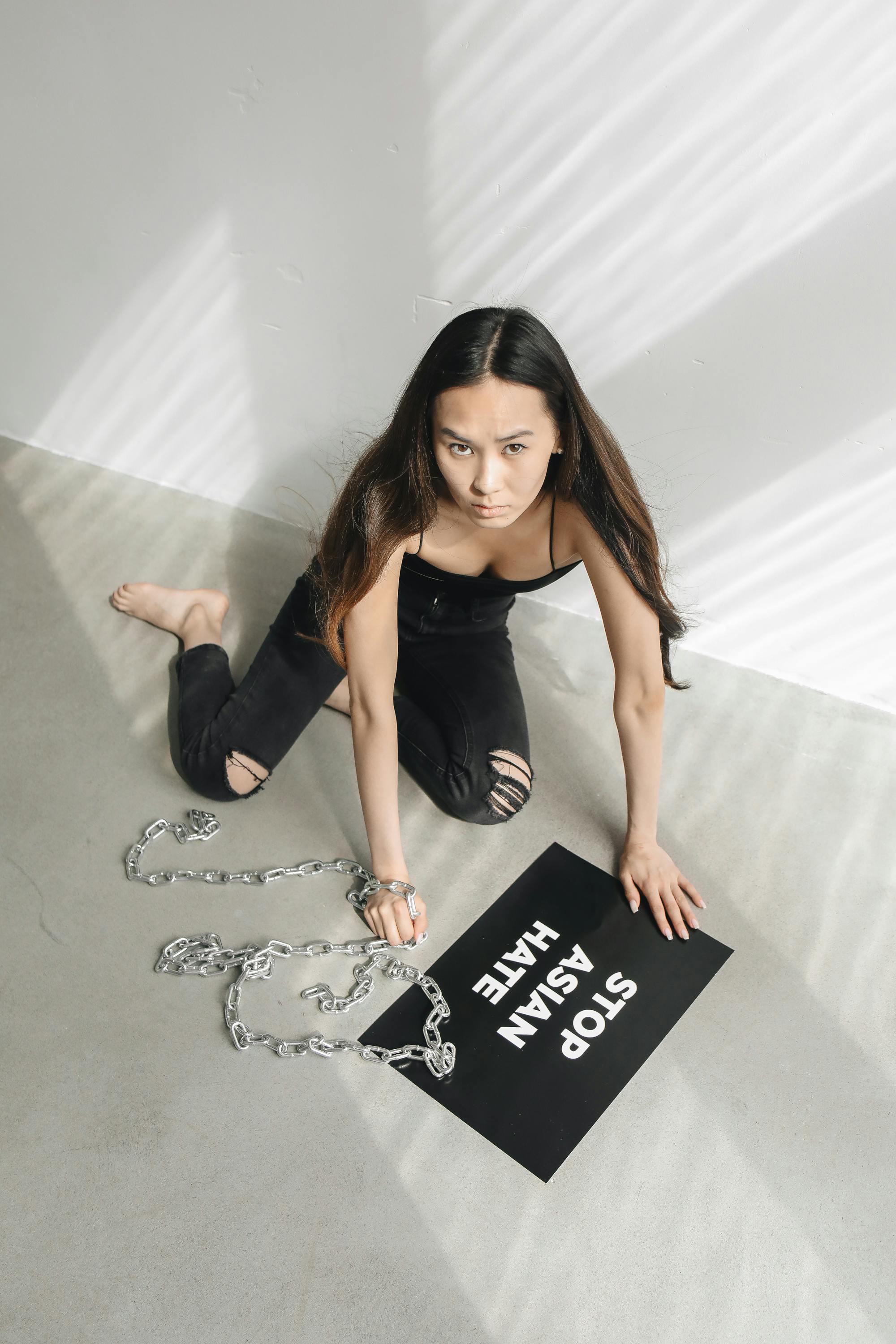 Woman in Tank Top and Ripped Black Jeans Sitting on Floor