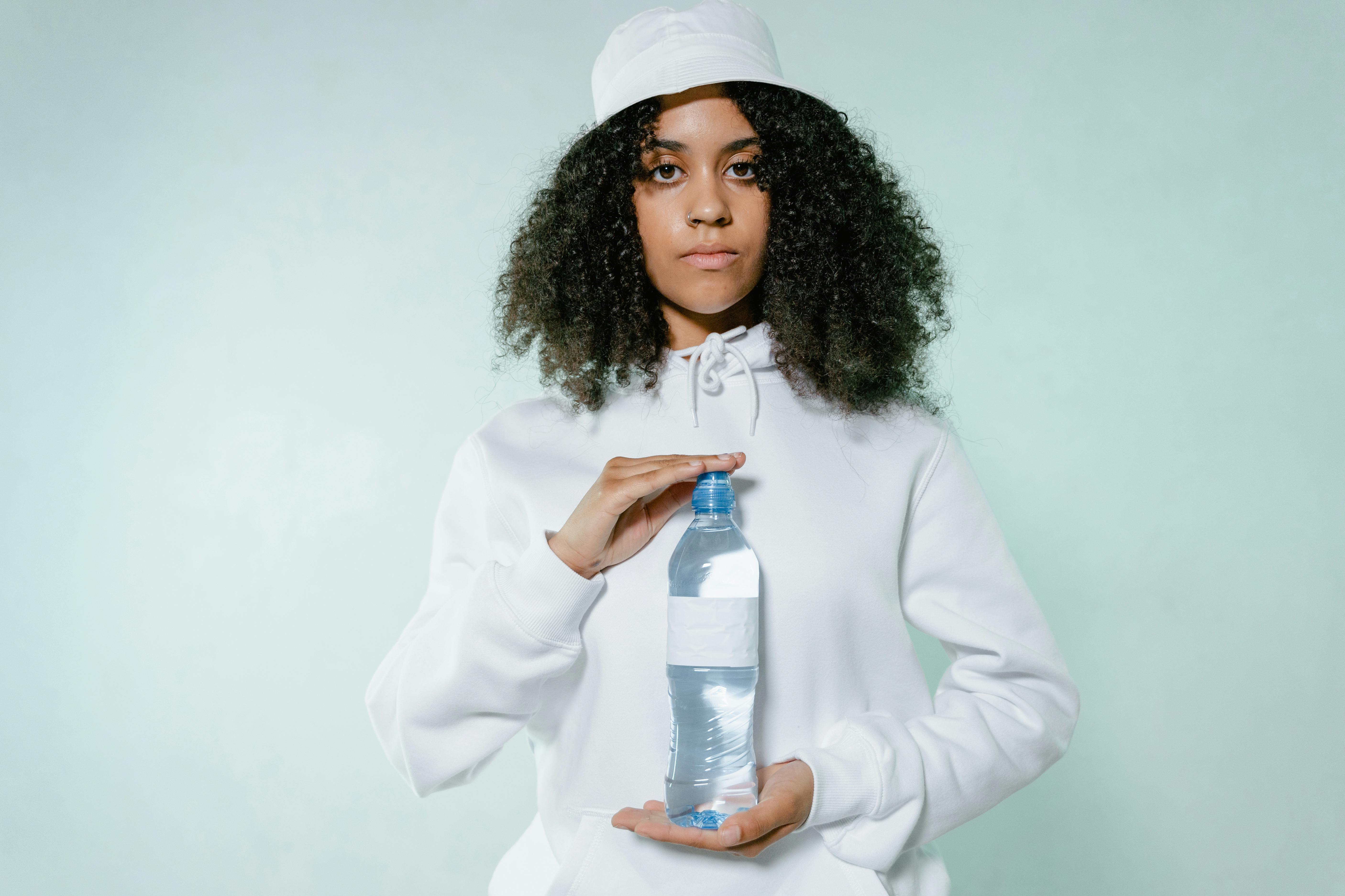 An Afro-Haired Woman in White Hoodie Holding a Bottle of Water