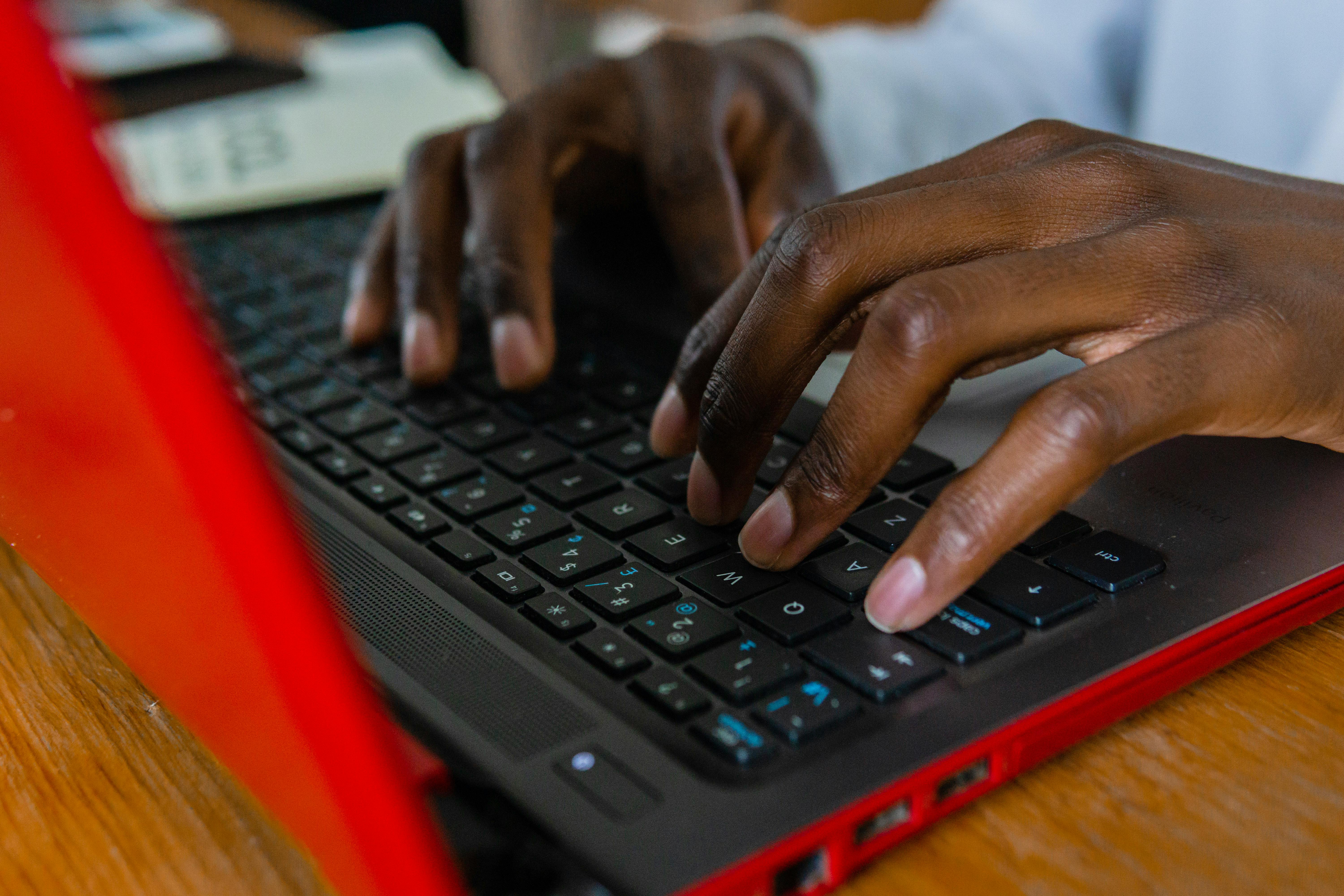 Person Using Black and Red Laptop Computer