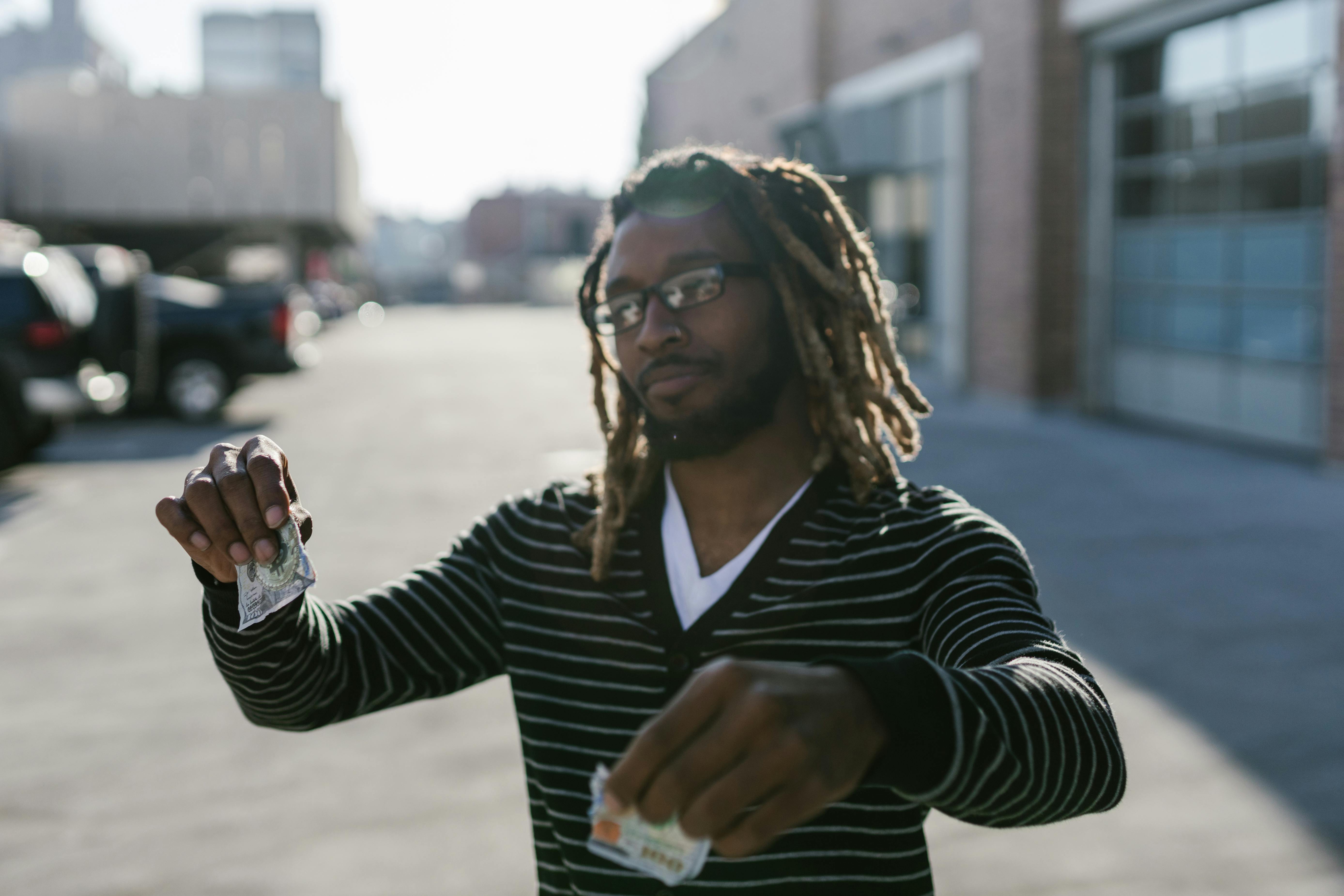 Man in Black Striped Long Sleeves Holding a Ripped Banknote