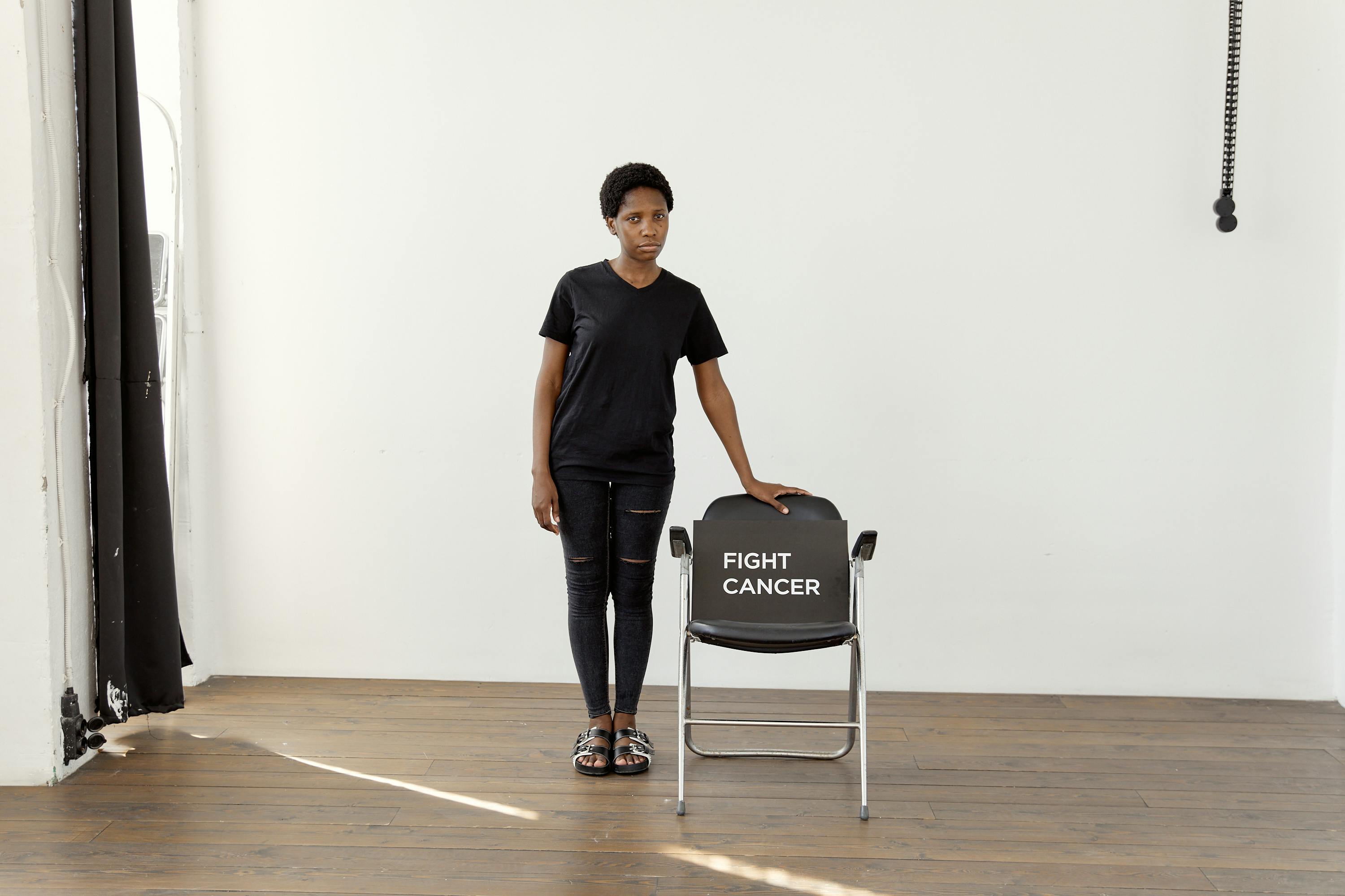 Woman Standing next to a Chair with a Sign Saying 