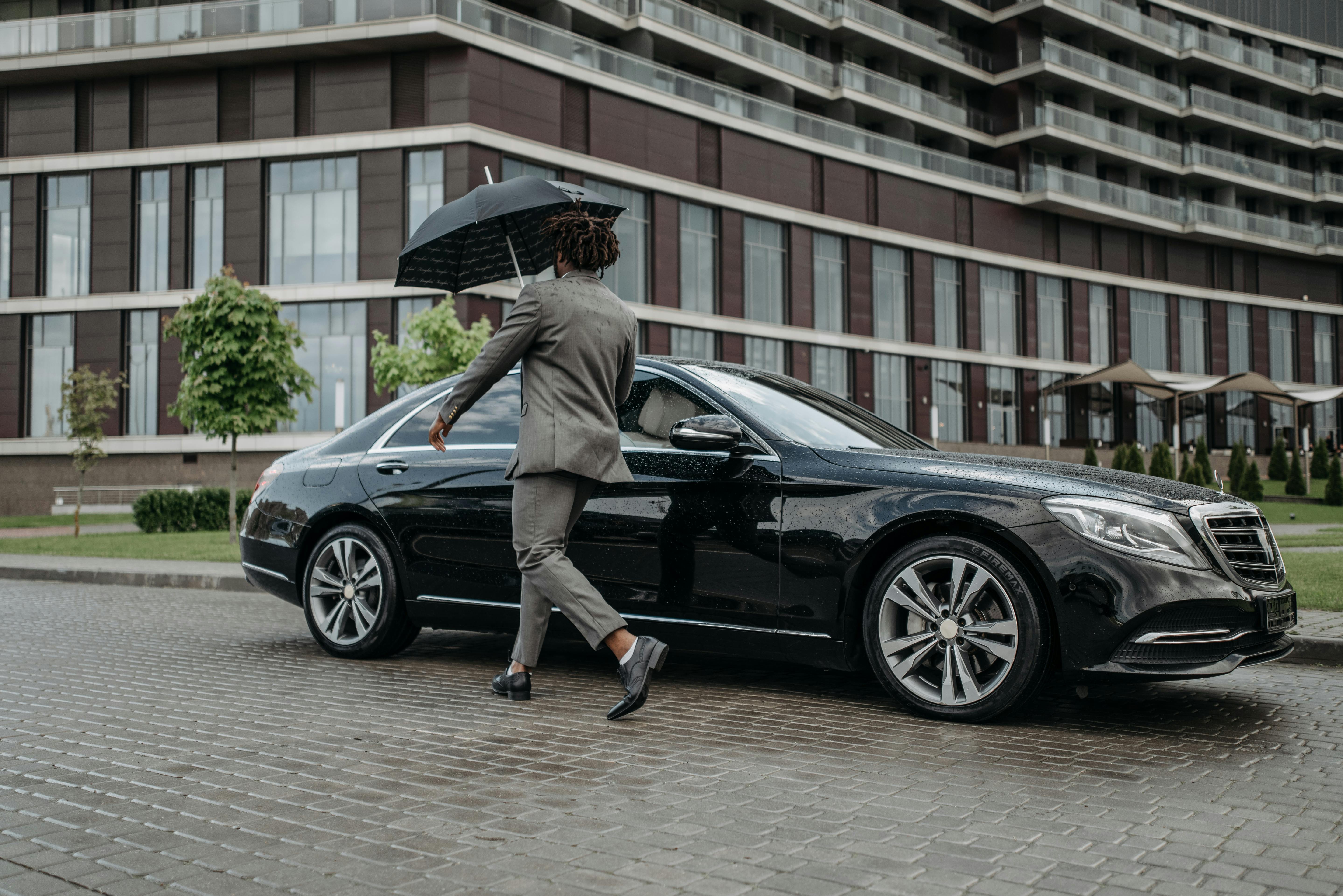 A Man in Gray Suit Opening the Door of a Black Car