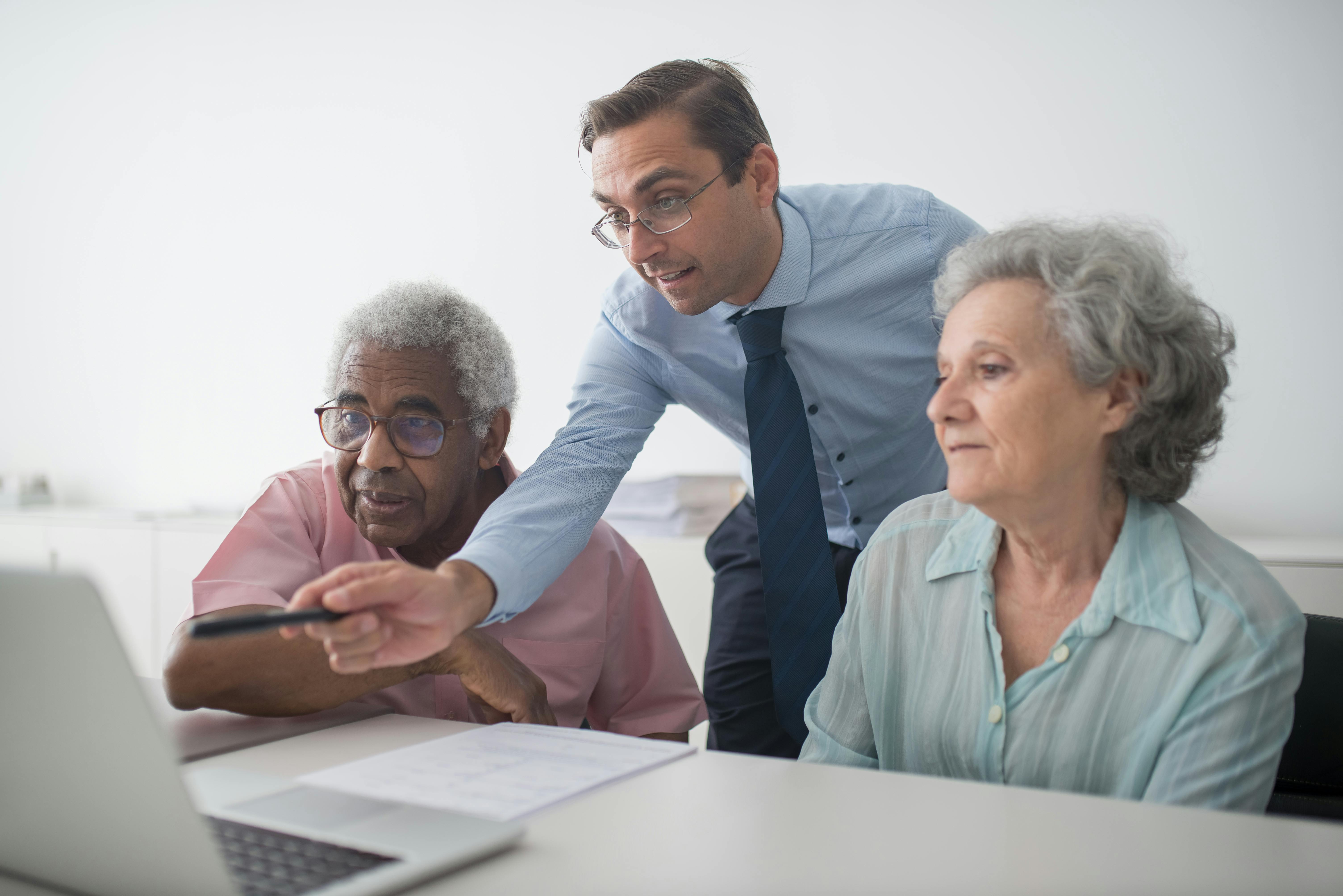 Insurance Agent Pointing at Laptop Screen for Elderly Clients