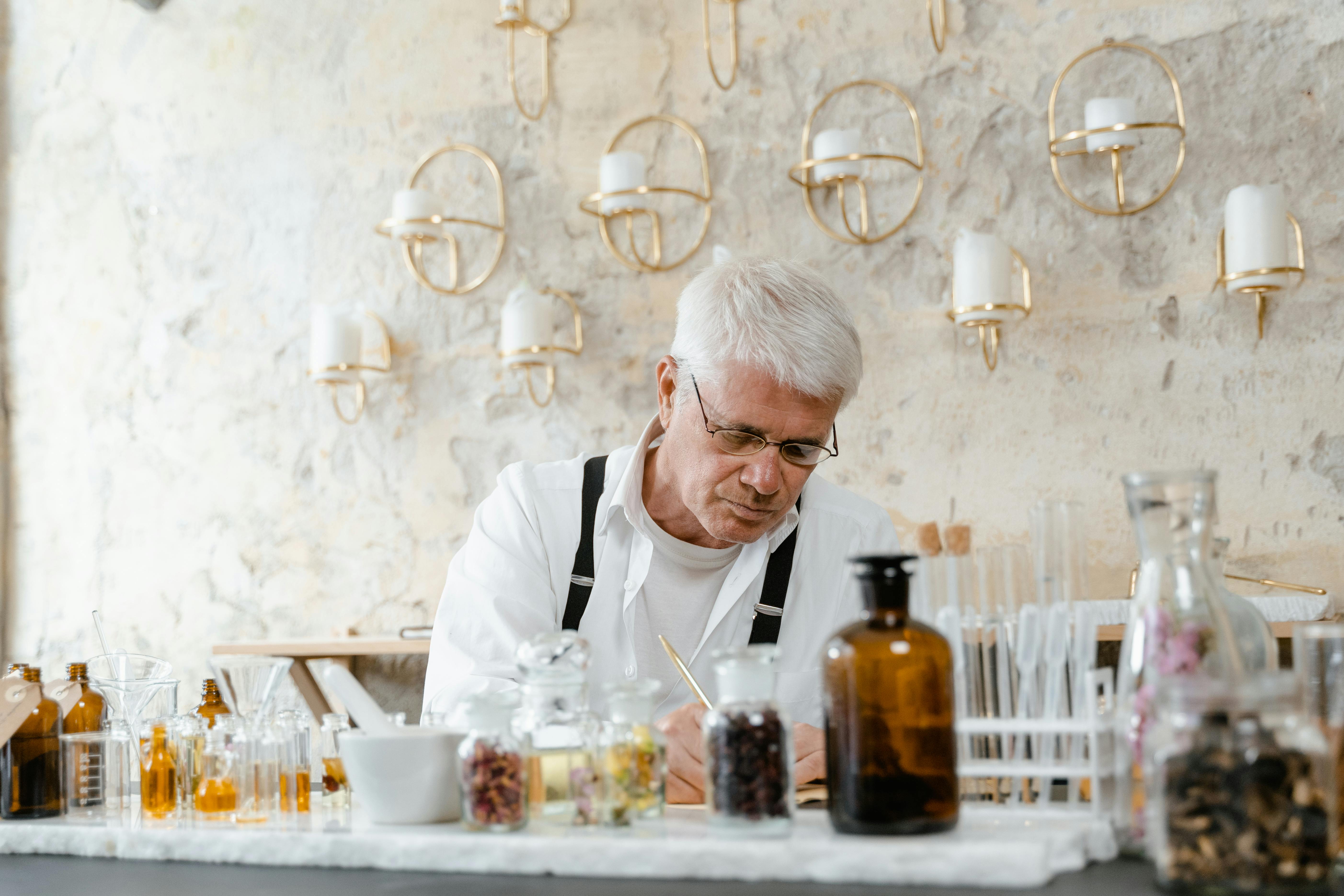 Man in White Dress Shirt Sitting on Chair in Front of Table With Bottles and Glasses