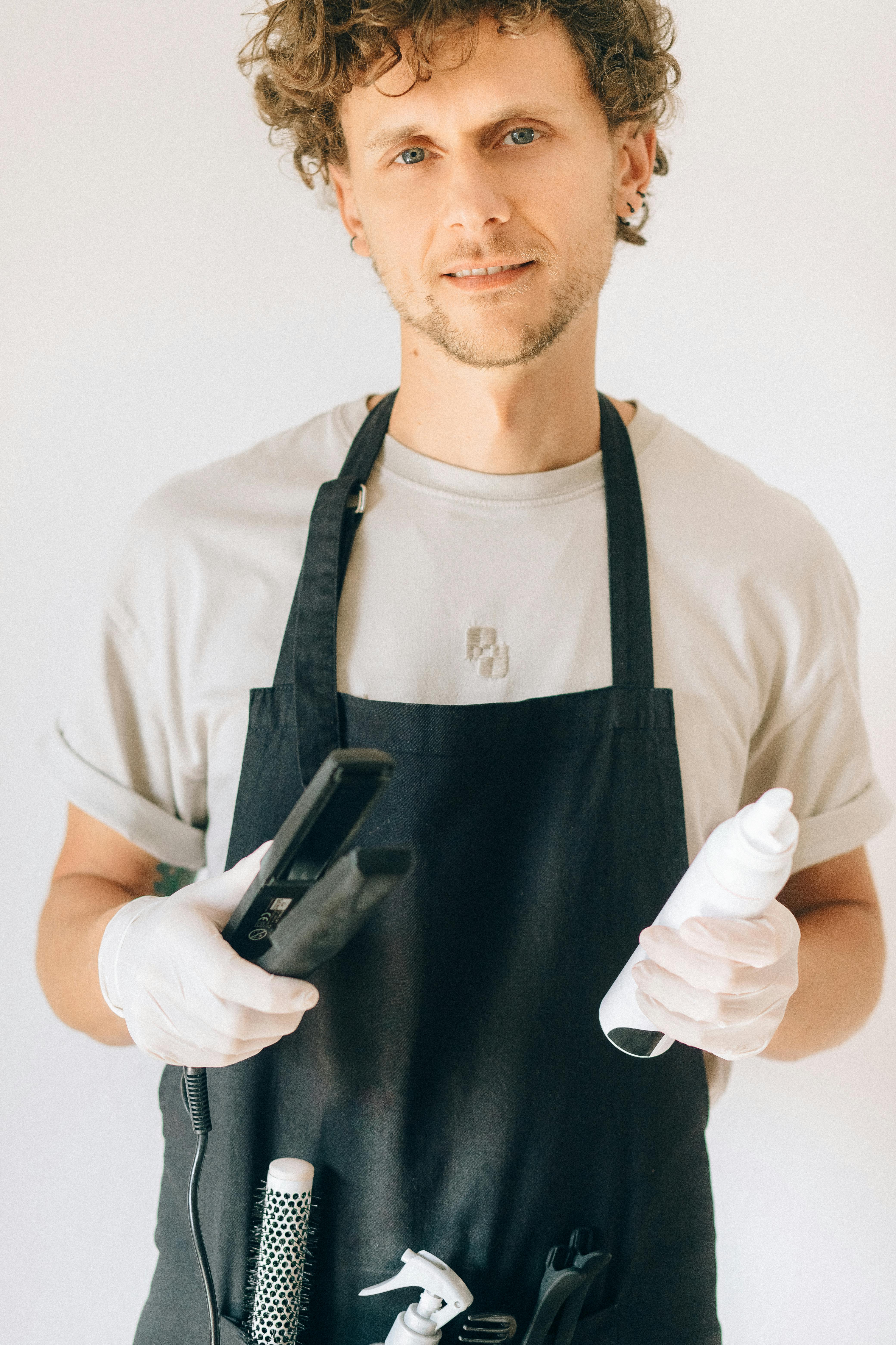 Man in Black Apron Holding Hair Straightener