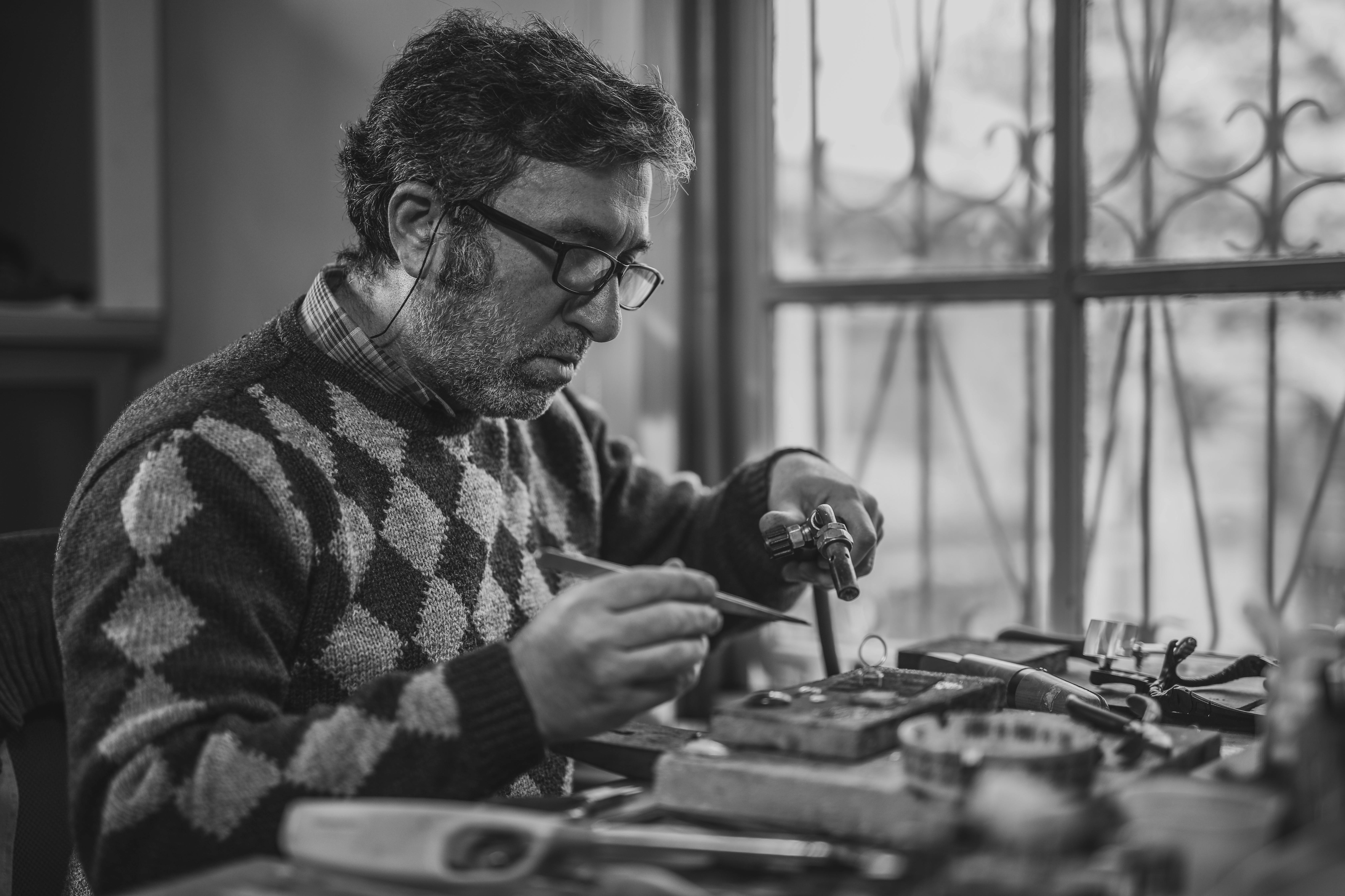 Grayscale Photo of Man Holding Tools