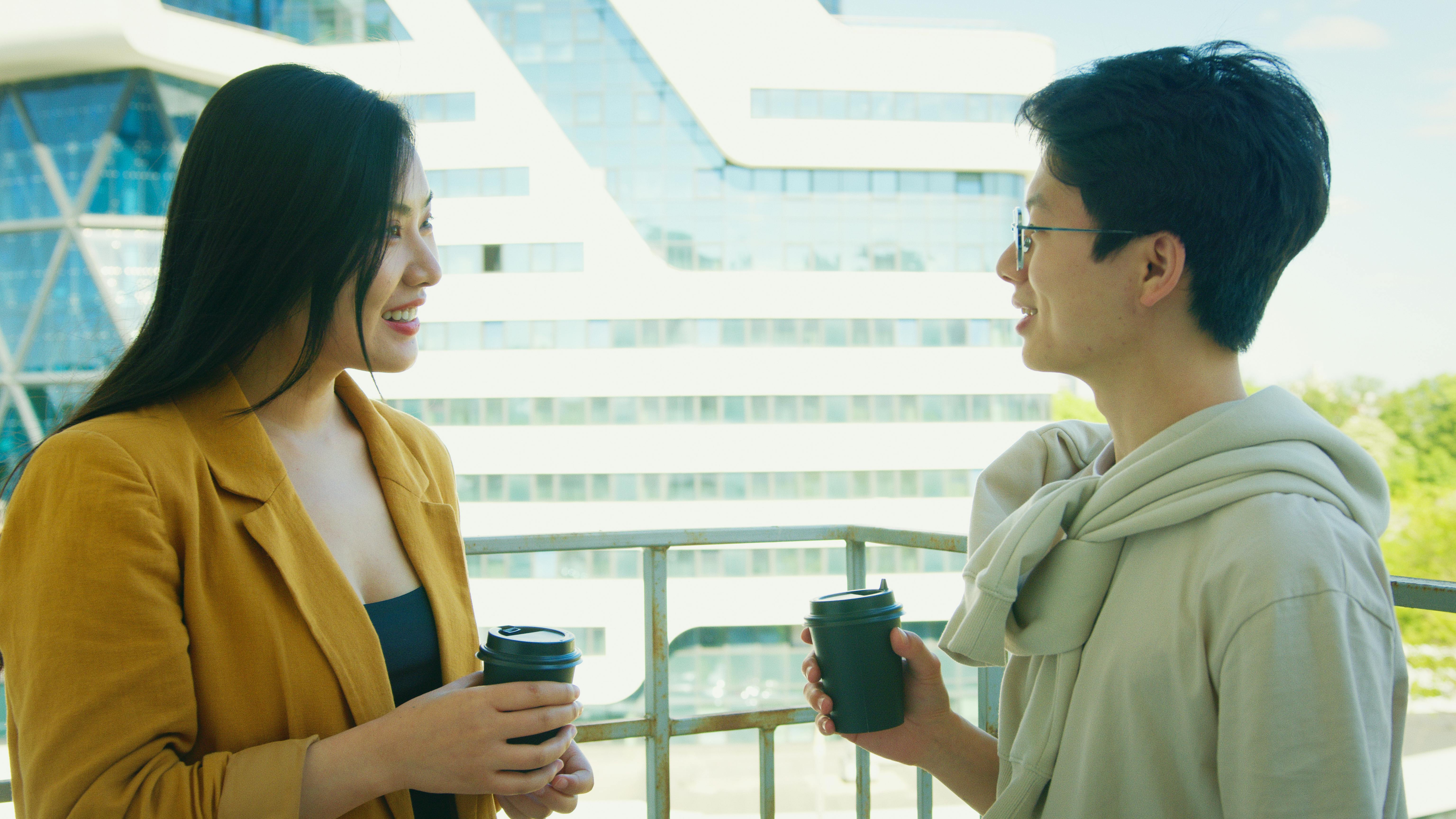 Man and Woman Holding Cups While Talking