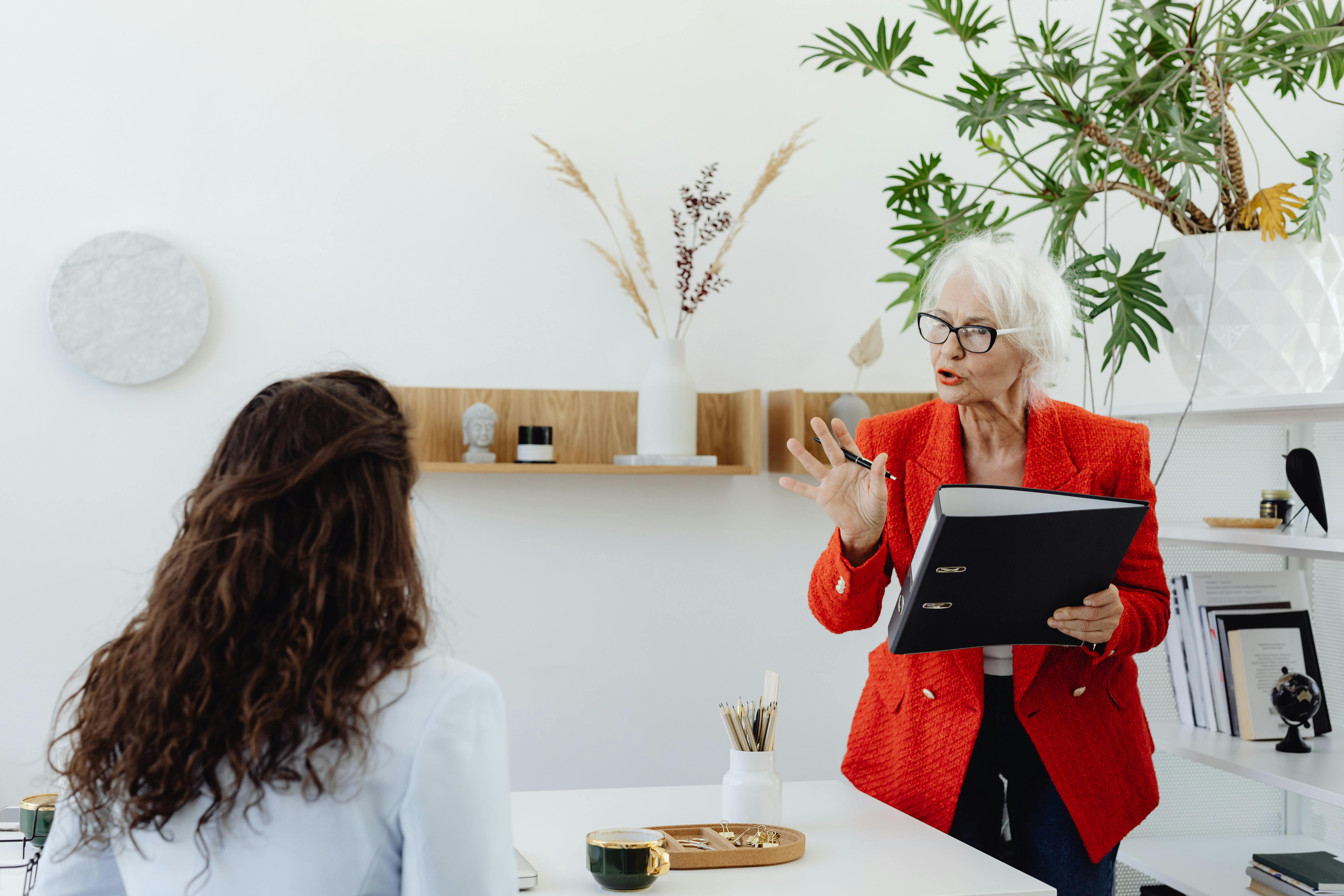 An Elderly Woman in a Red Blazer Discussing to Another Woman