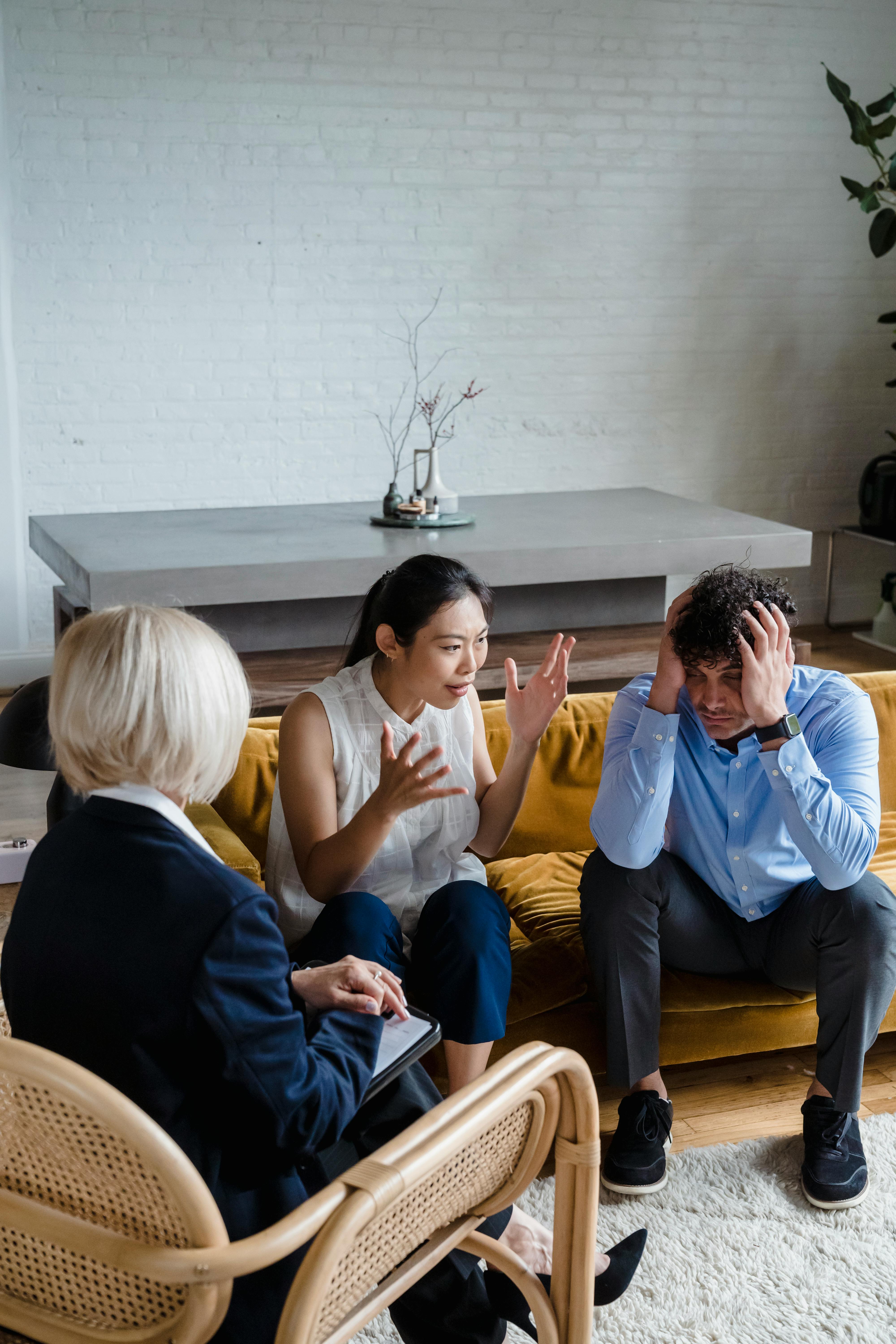 A Couple Having a Discussion in front of a Woman Sitting on a Chair