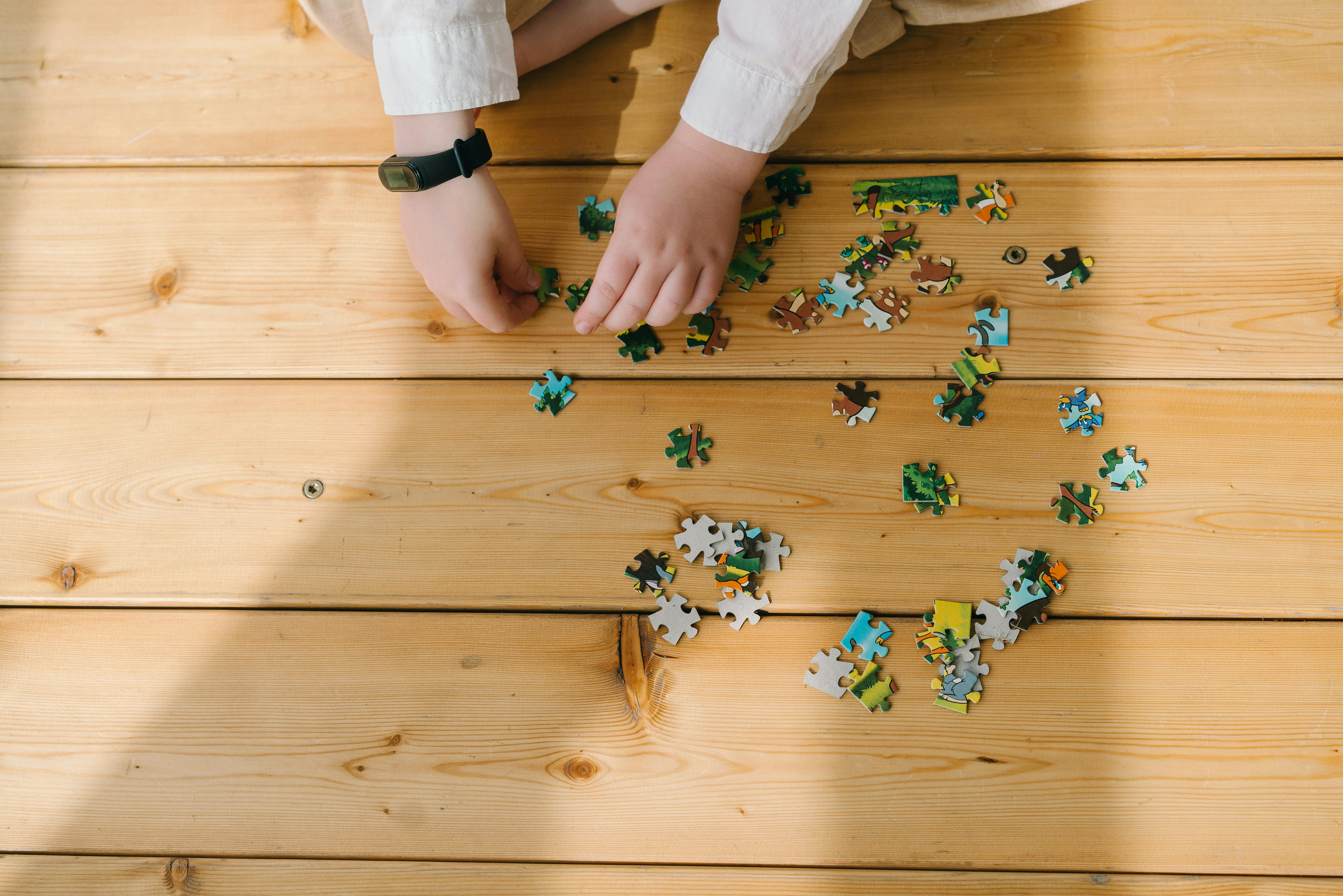 A Person Playing Puzzle on Wooden Floor