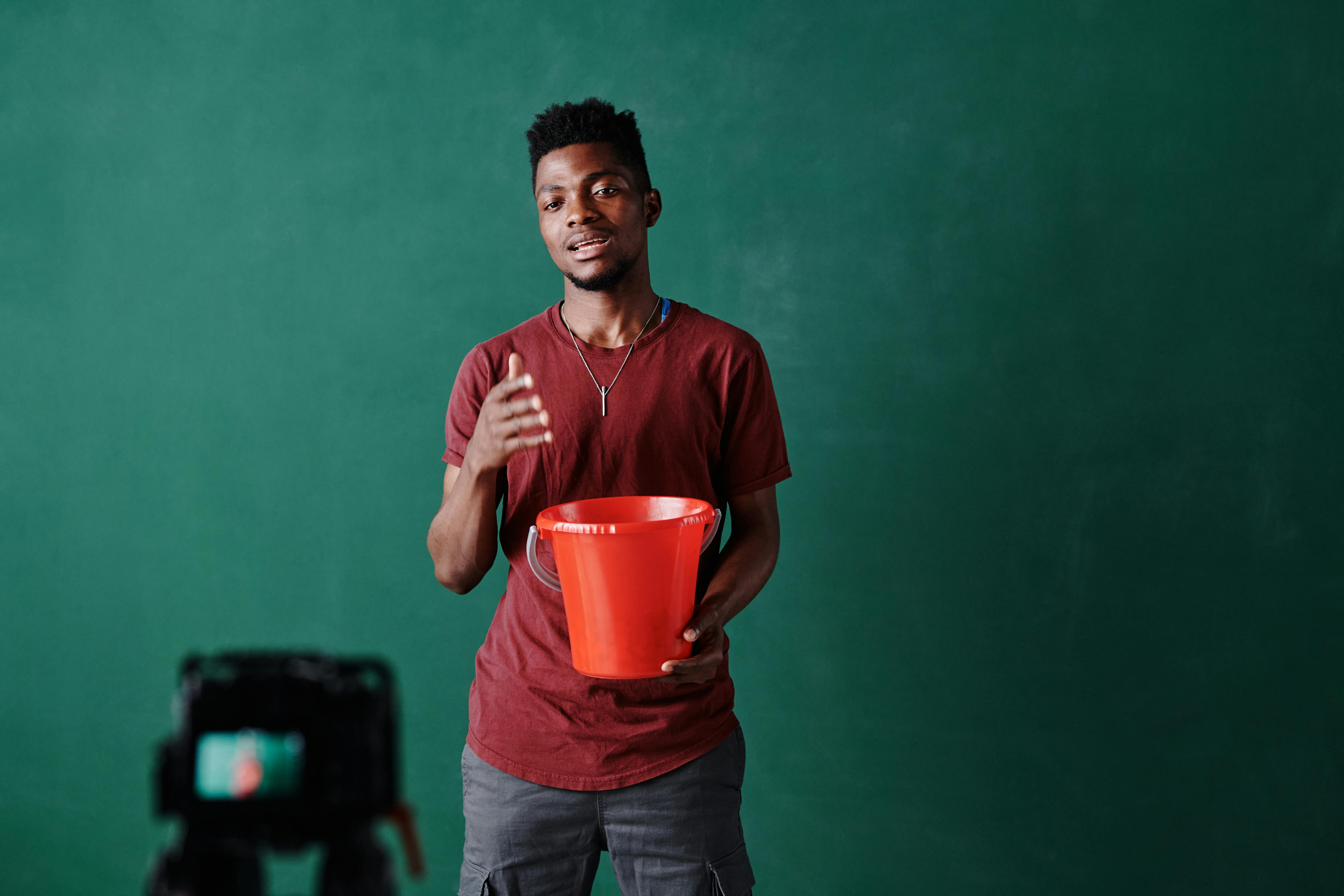 Man in T-shirt Holding a Red Bucket