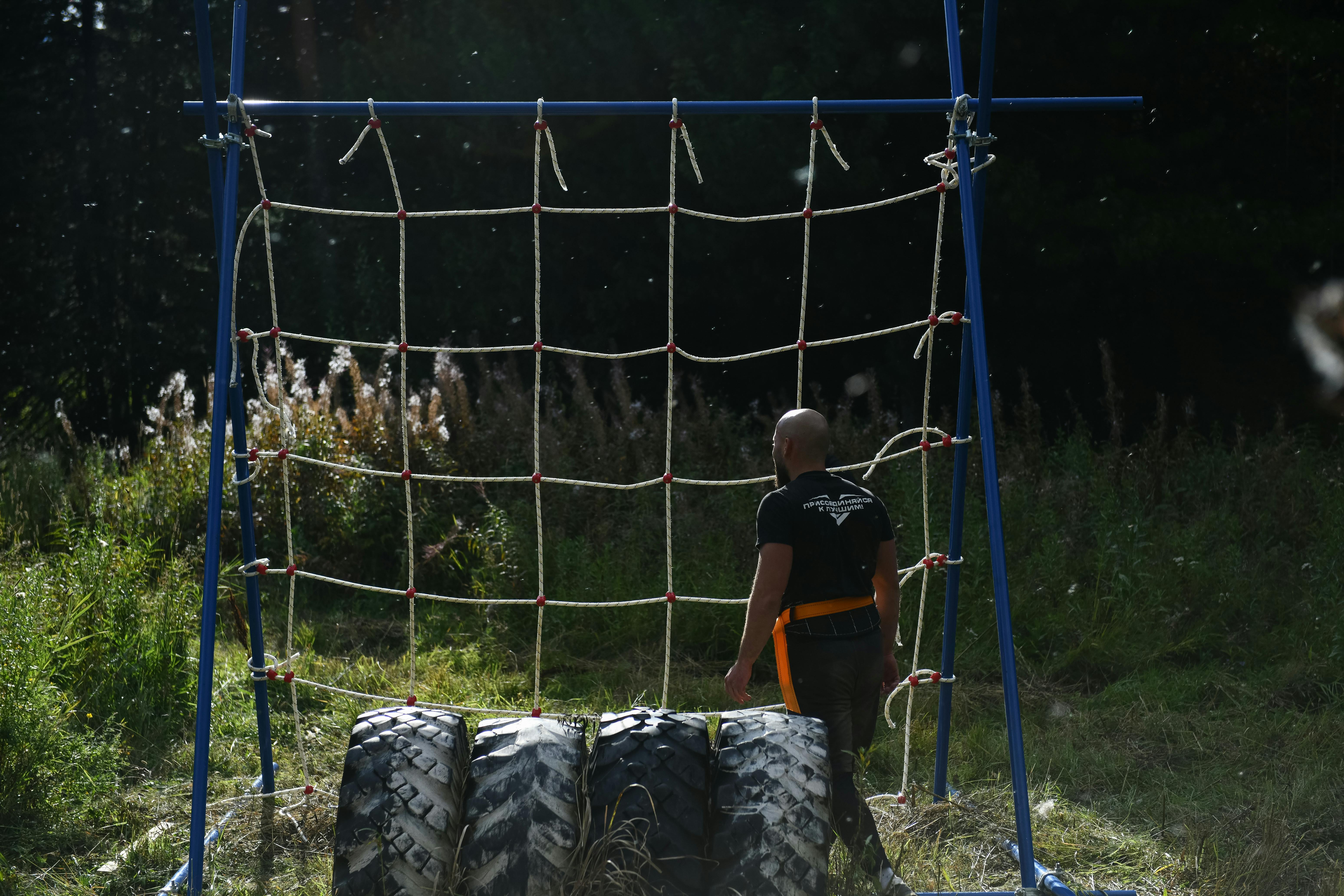 Man in Black T-shirt Standing Beside a Net of an Obstacle Course