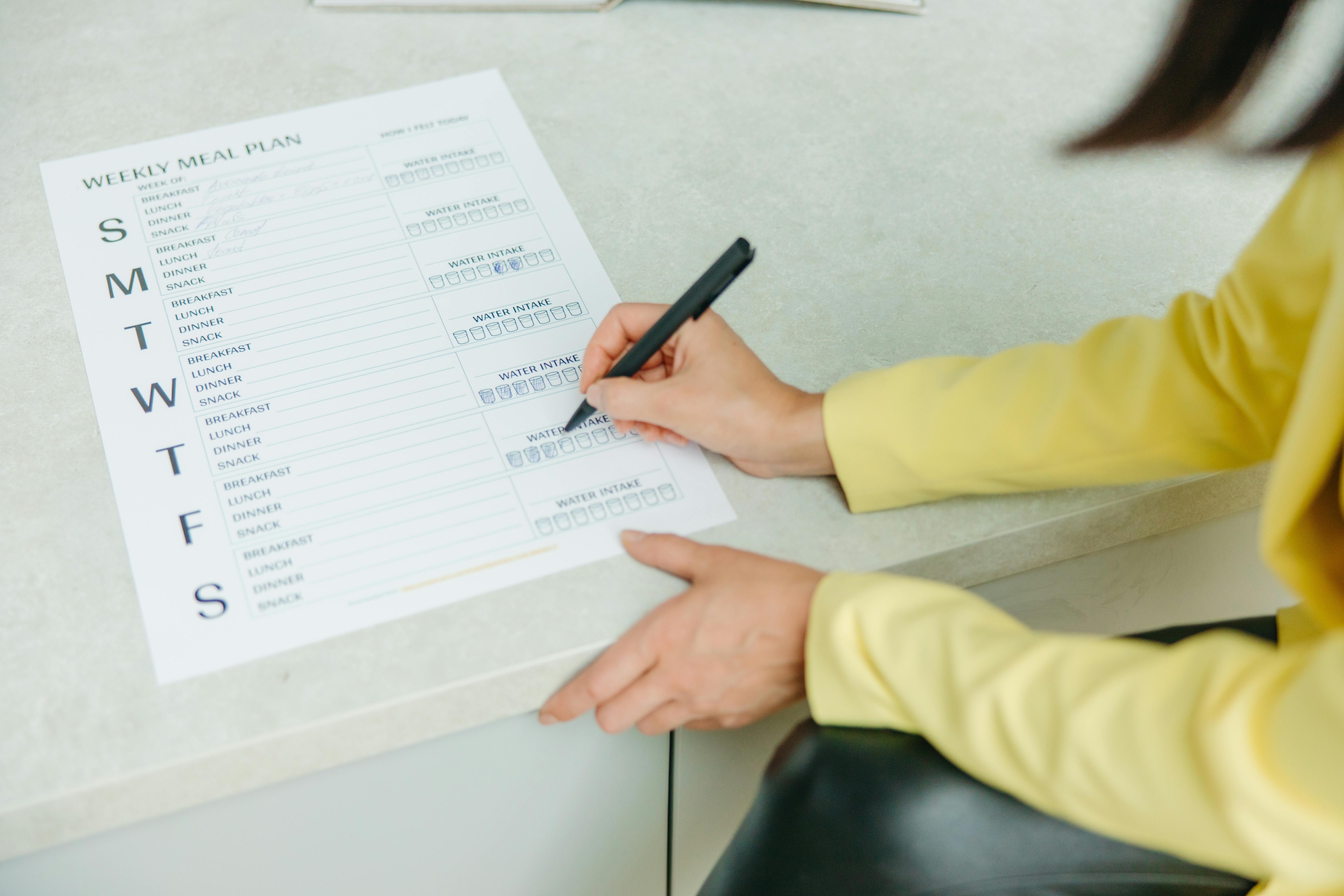 A Person Holding a Black Pen Writing on White Paper.