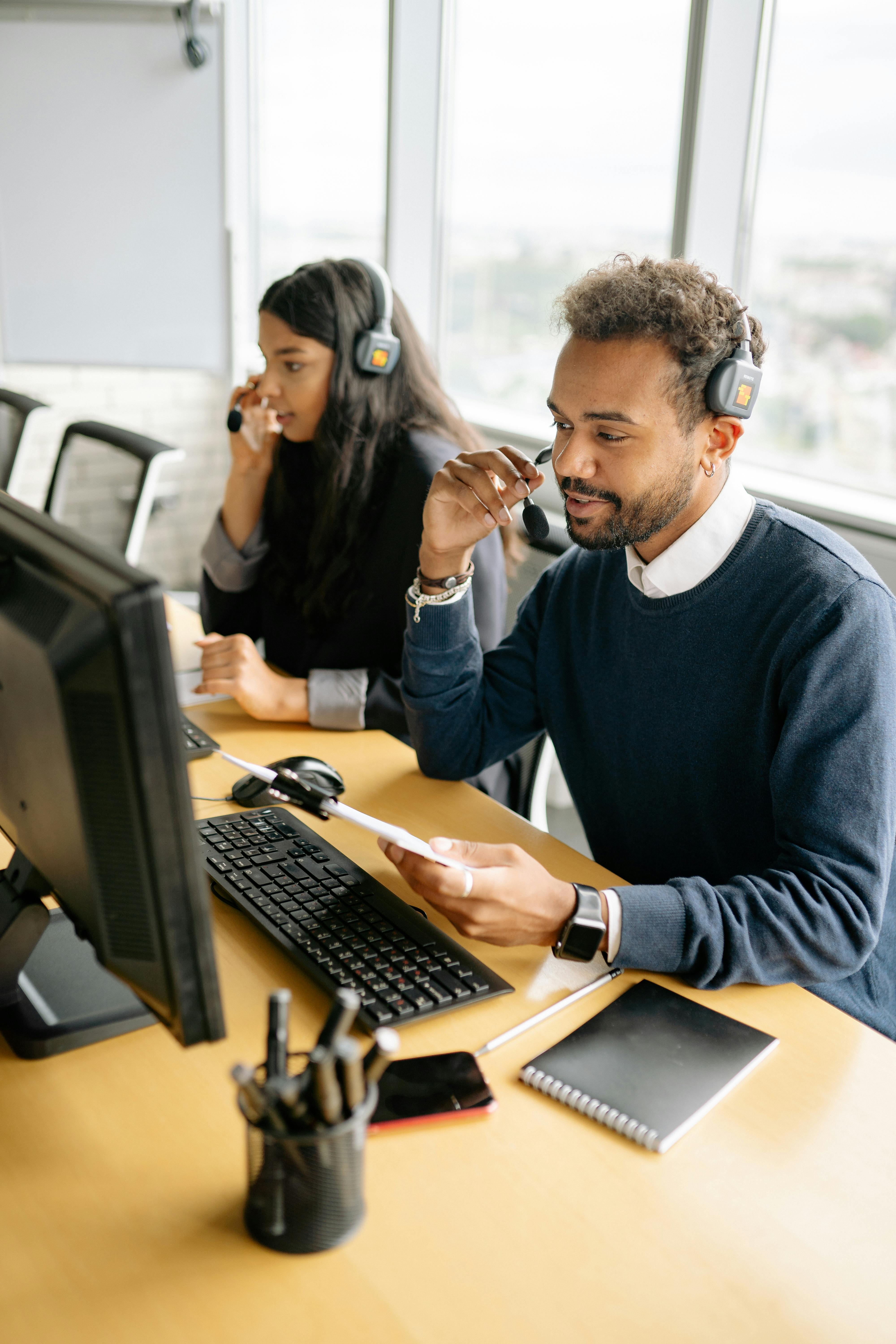 Man and Woman Wearing Headphones while Working in the Office