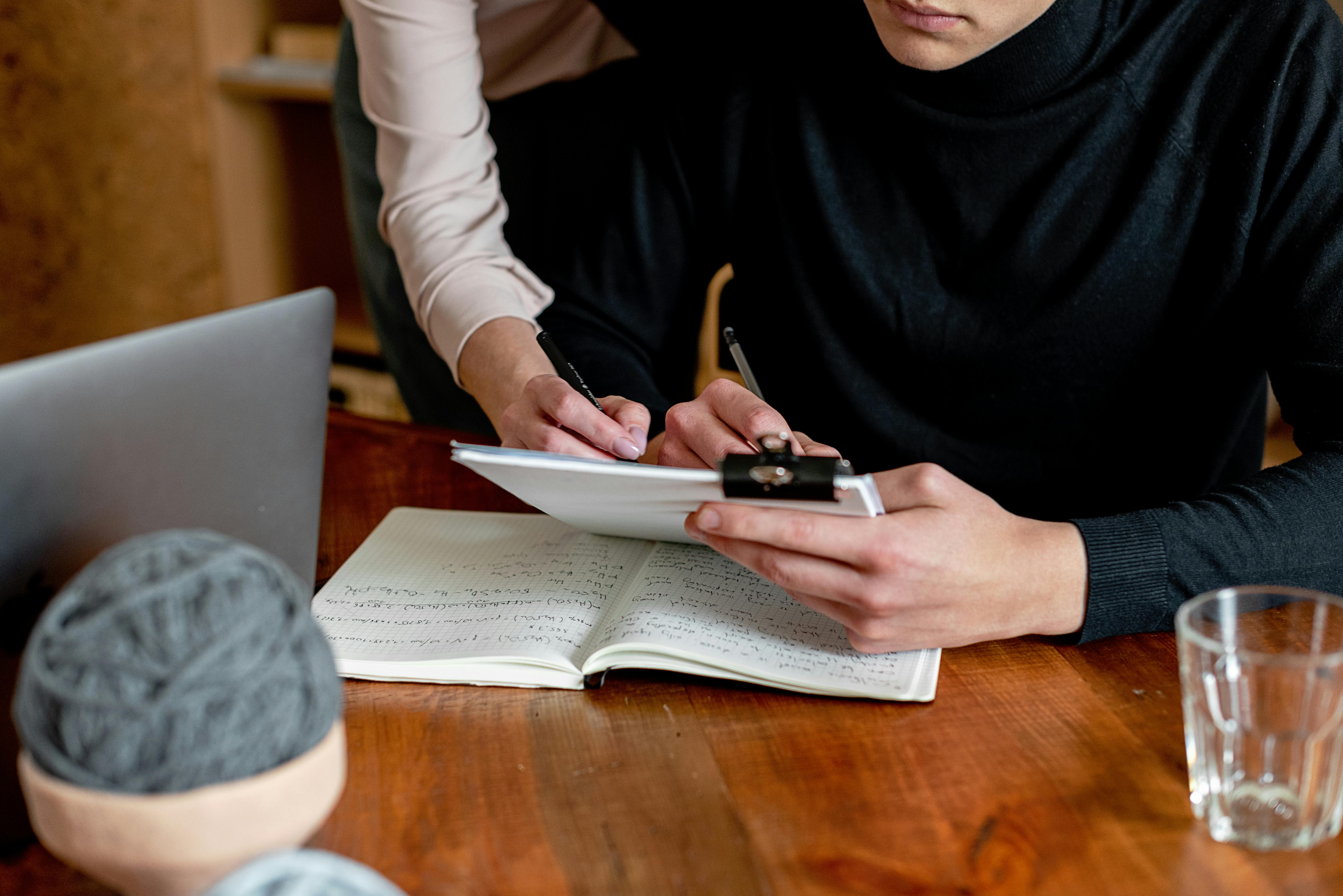 Woman over Man Writing on Table