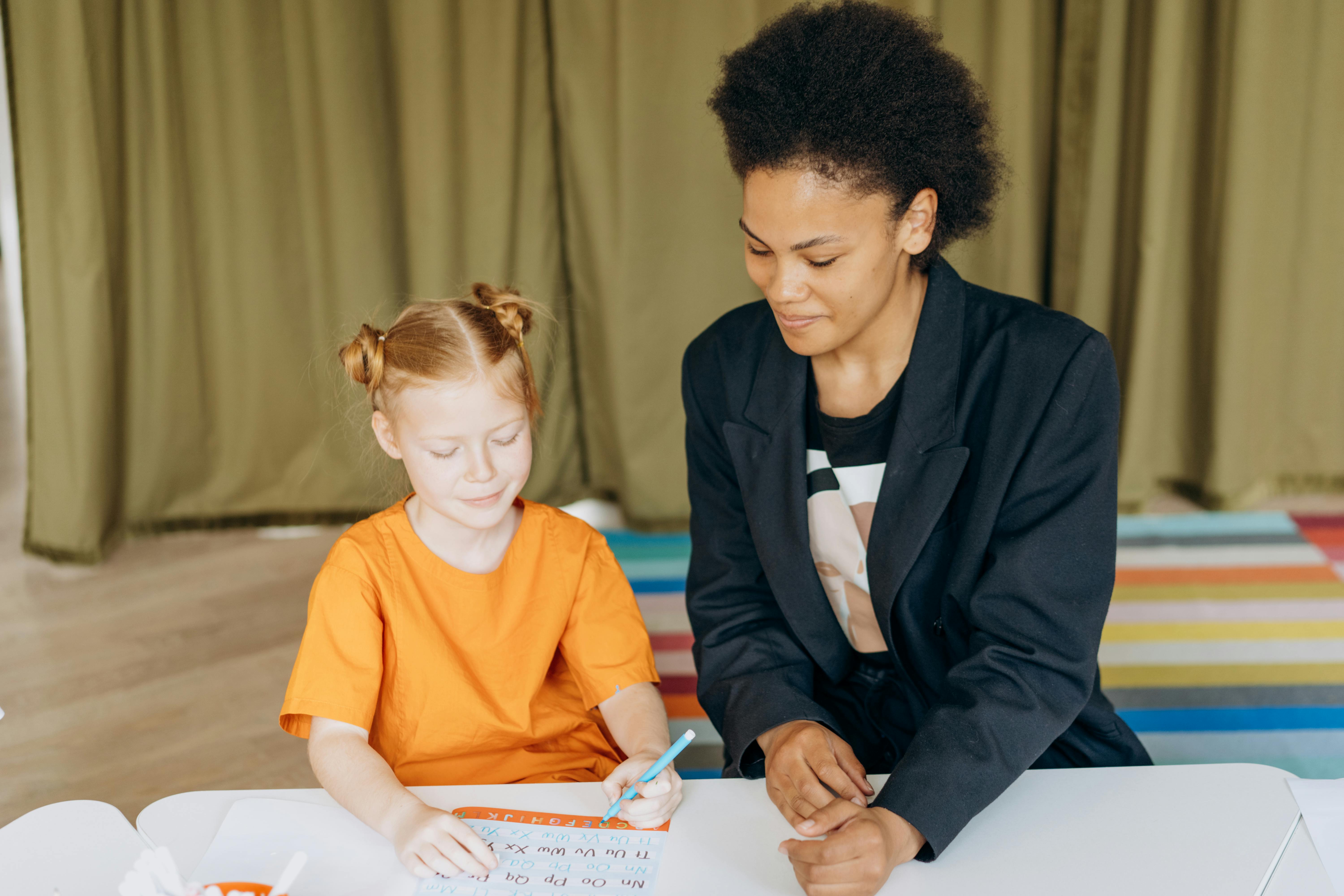 A Woman Wearing Blazer Sitting Beside the Student