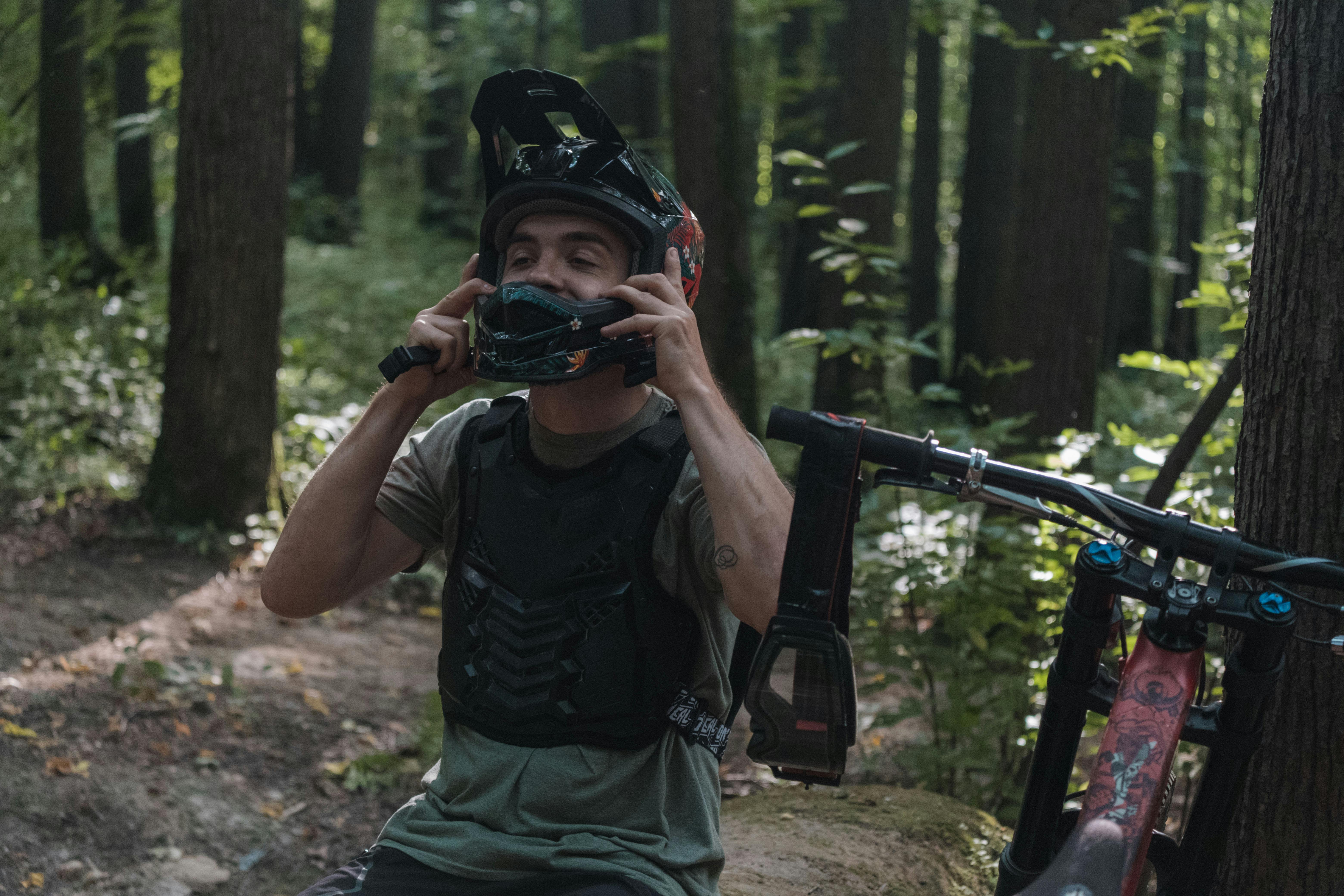 A Biker Taking off his Helmet in the Woods