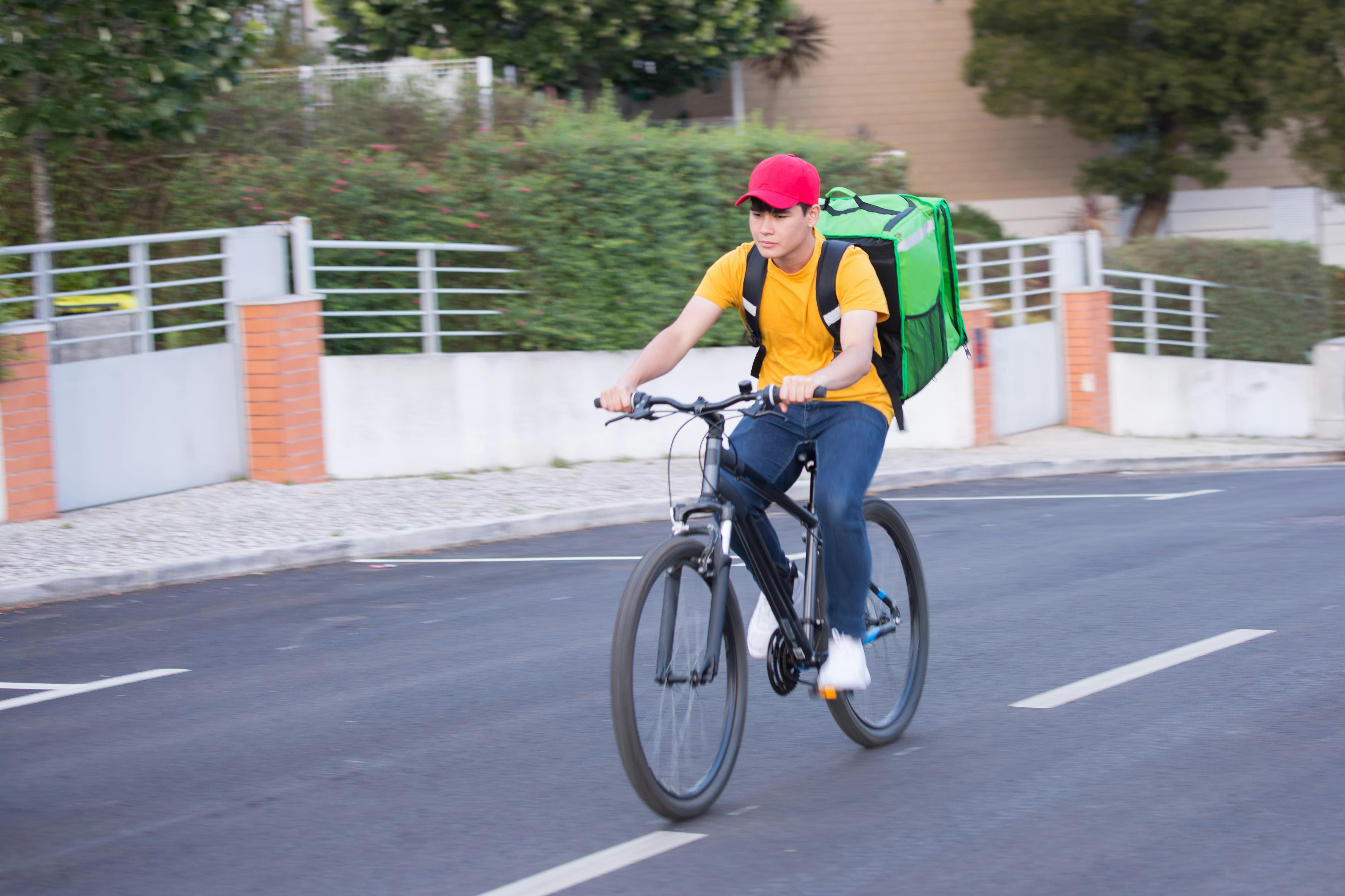 Man in Yellow Shirt Riding a Black Bicycle on Road