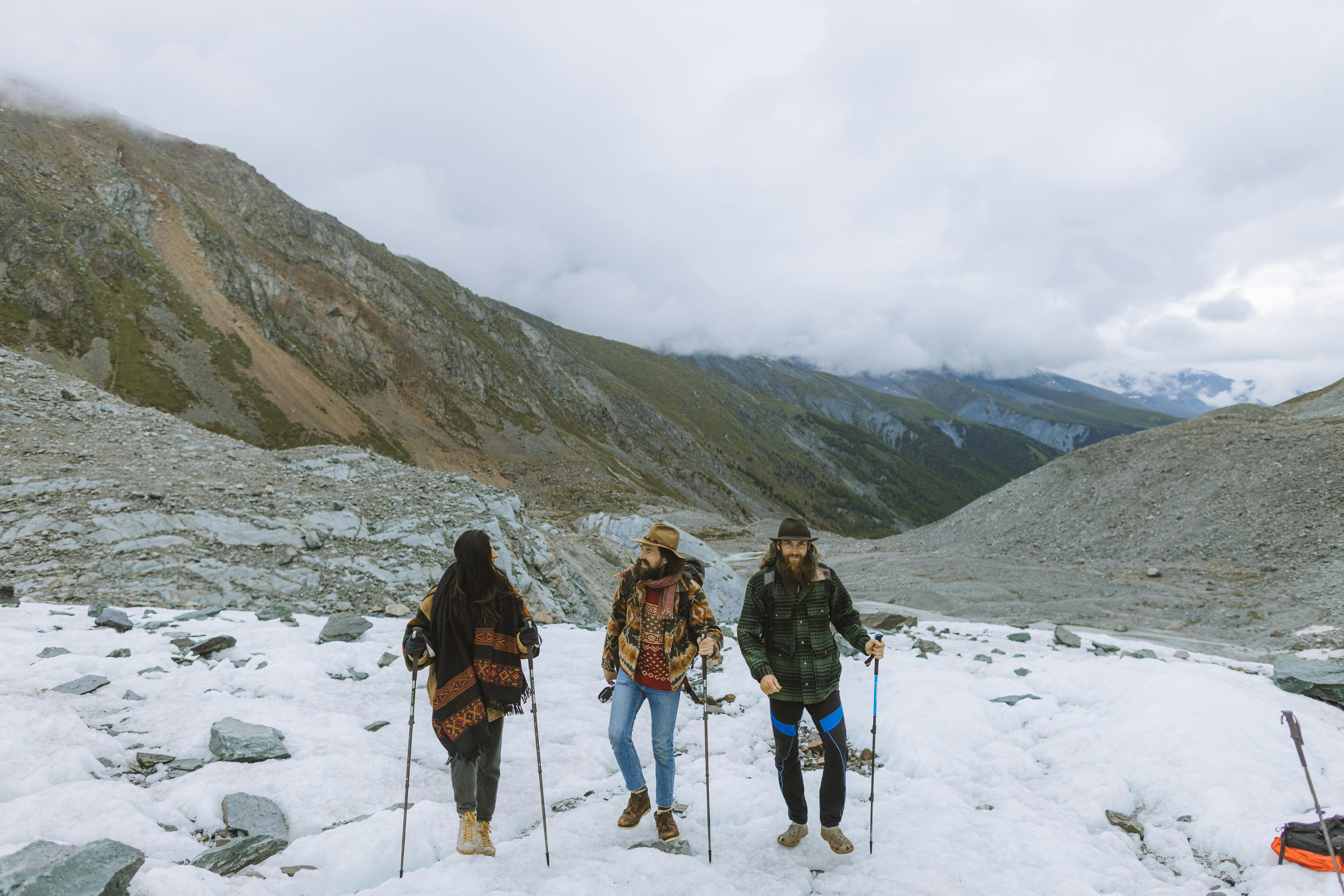 Three People Walking on Snow Covered Mountain