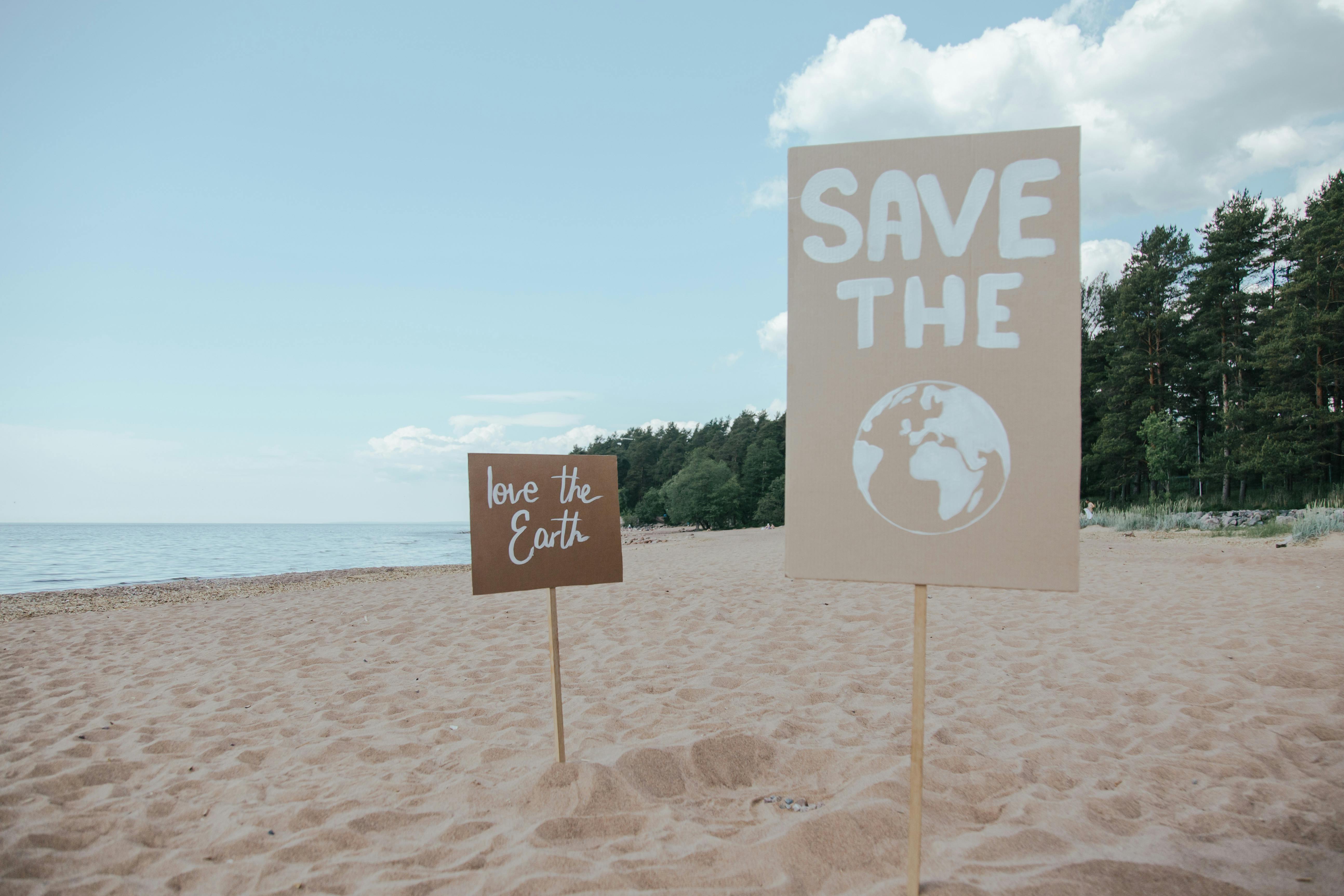 Signages With The Words Save The Earth and Love The Earth Planted on the Seashore