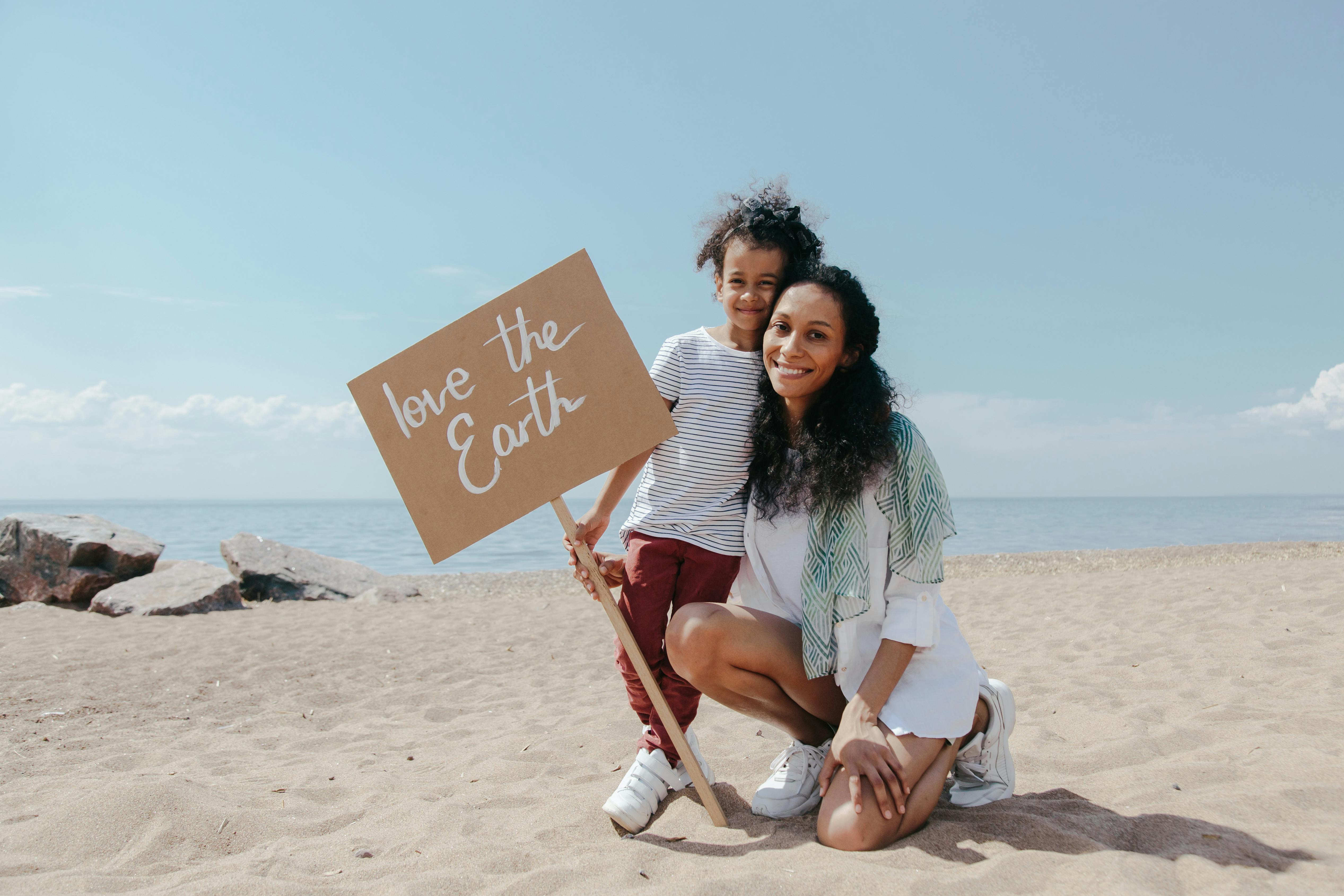 A Mother and Her Child Holding a Signage on The Beach