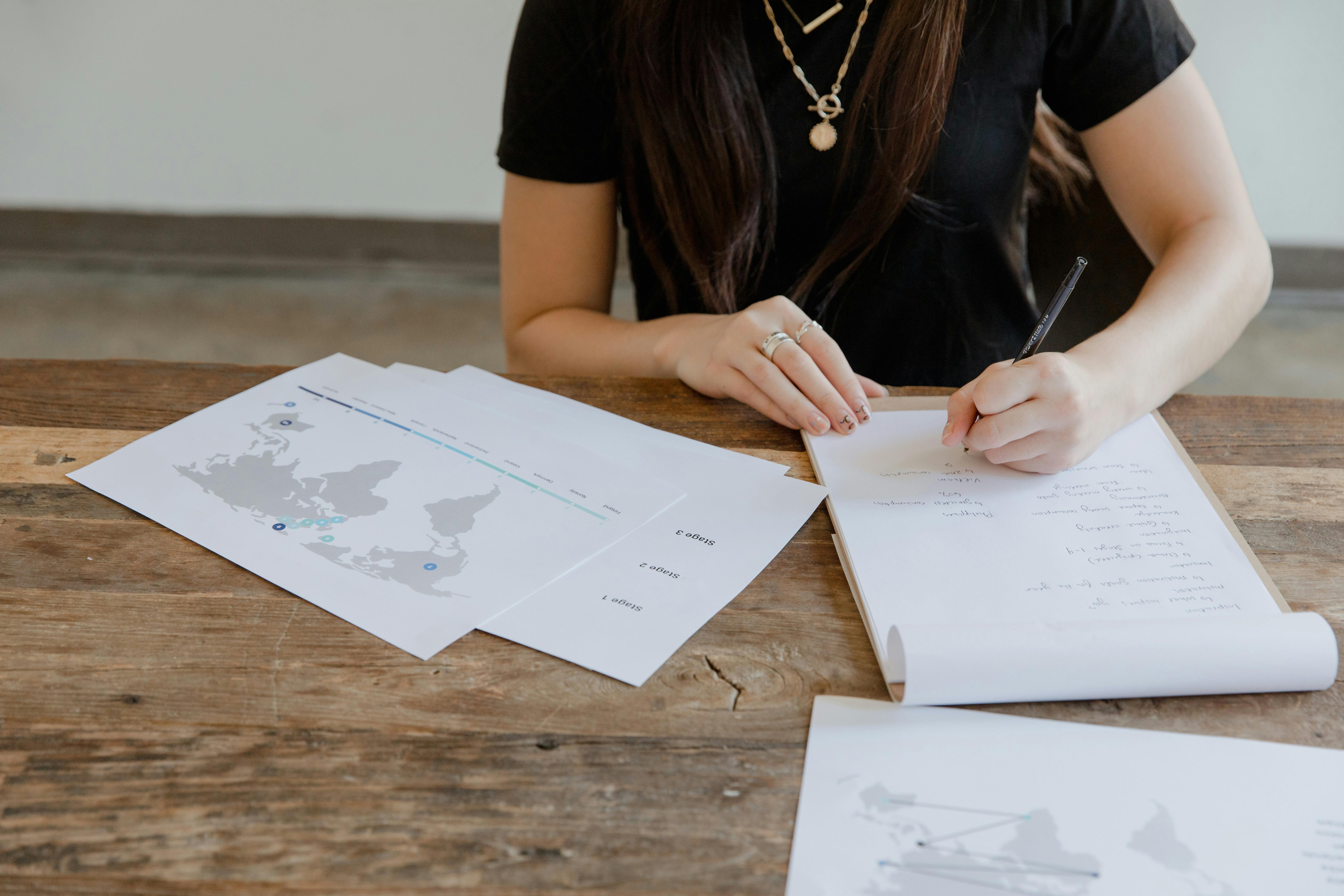 Woman in Black Shirt Writing on White Paper