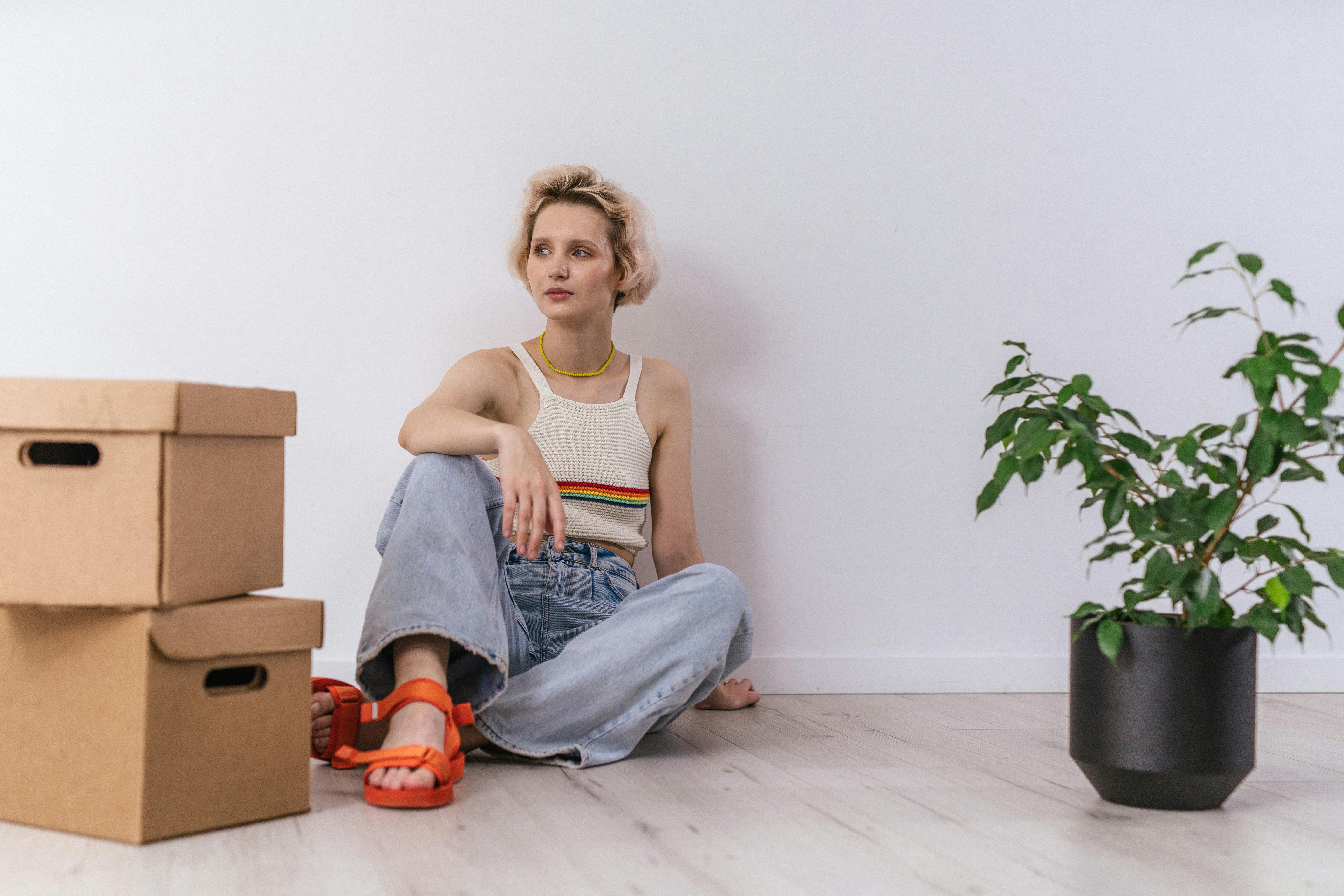 A Woman Sitting on the Floor next to Cardboard Boxes