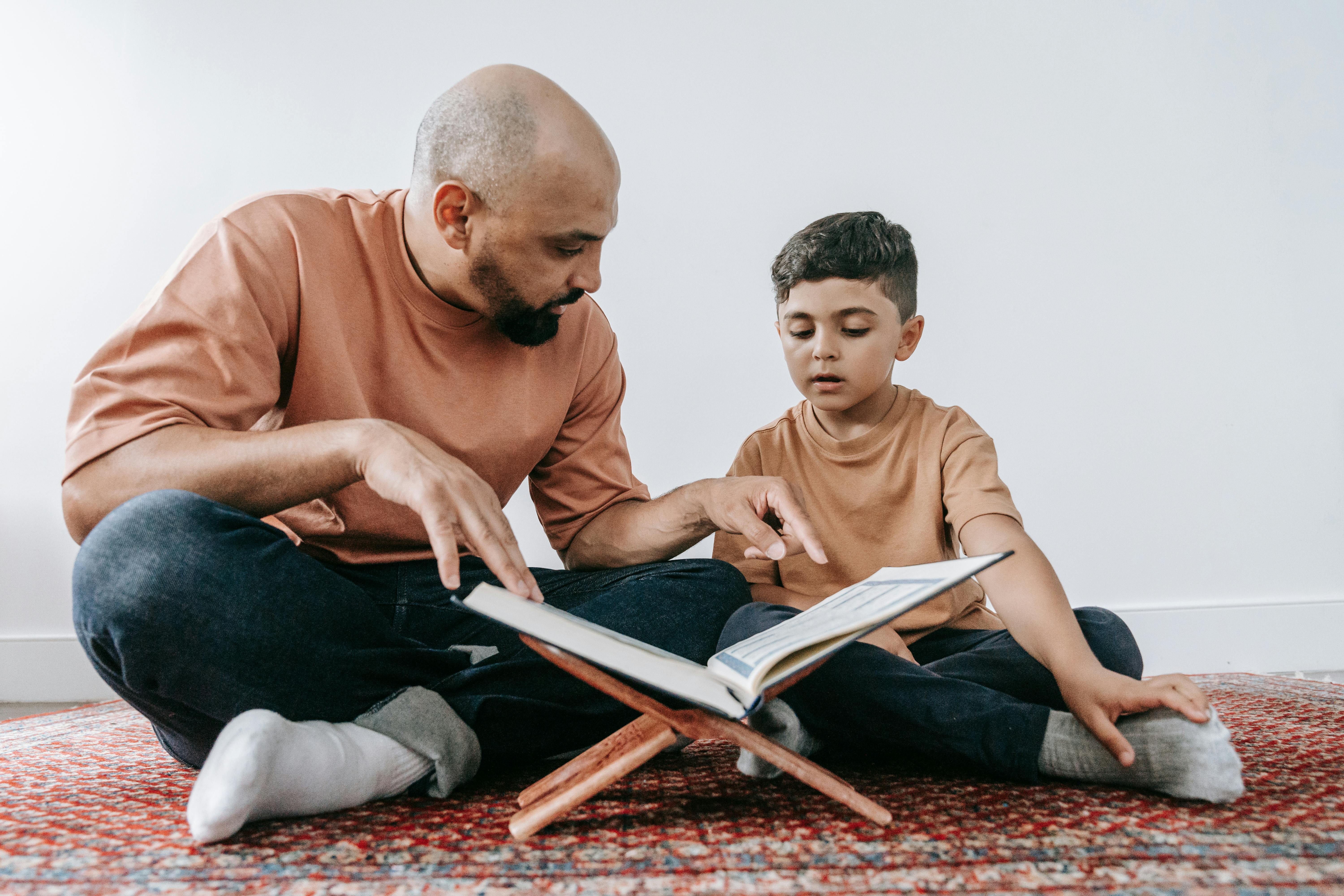 Man and Boy Sitting on Red and White Carpet