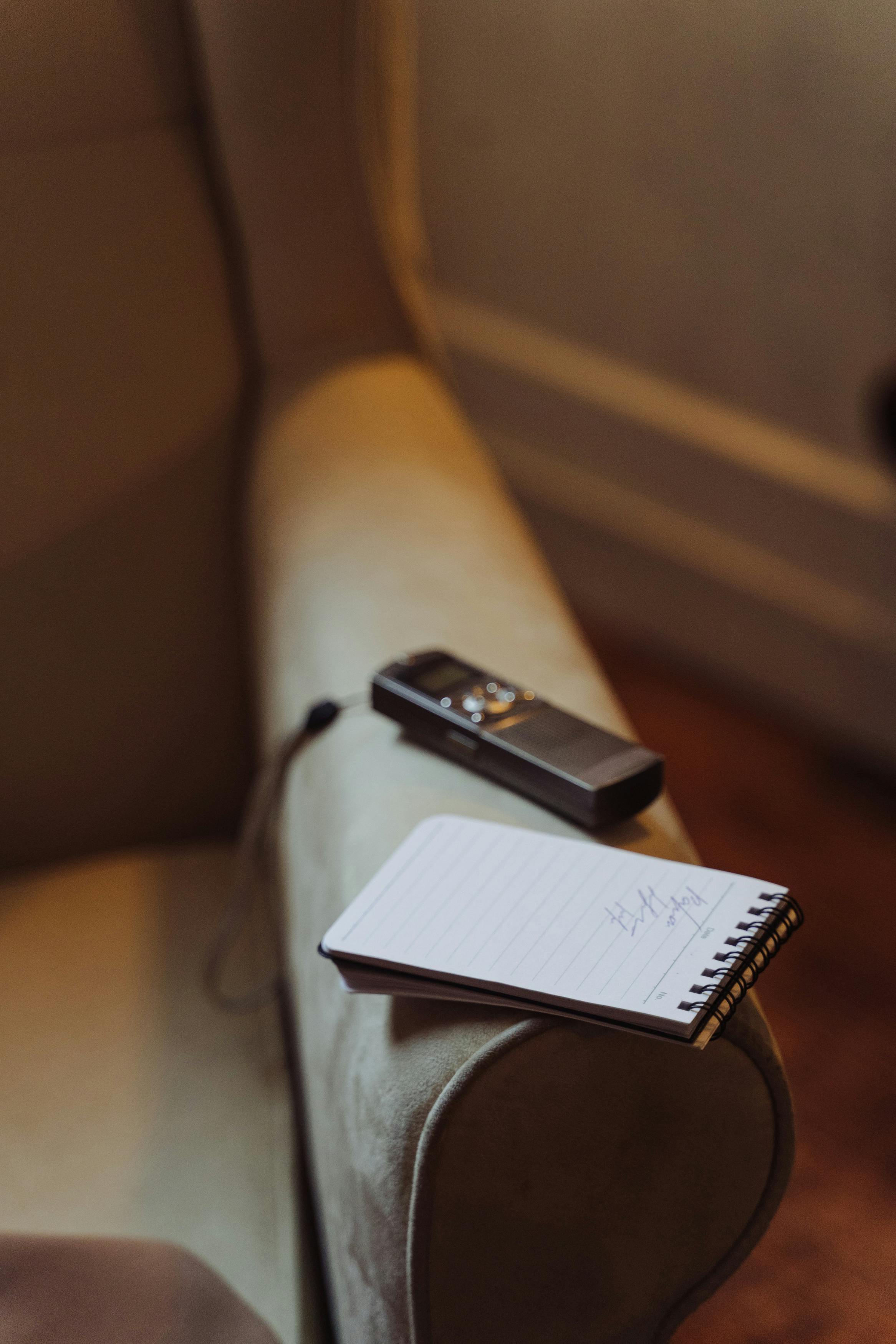 Spiral Notebook and Voice Recorder on Sofa Chair