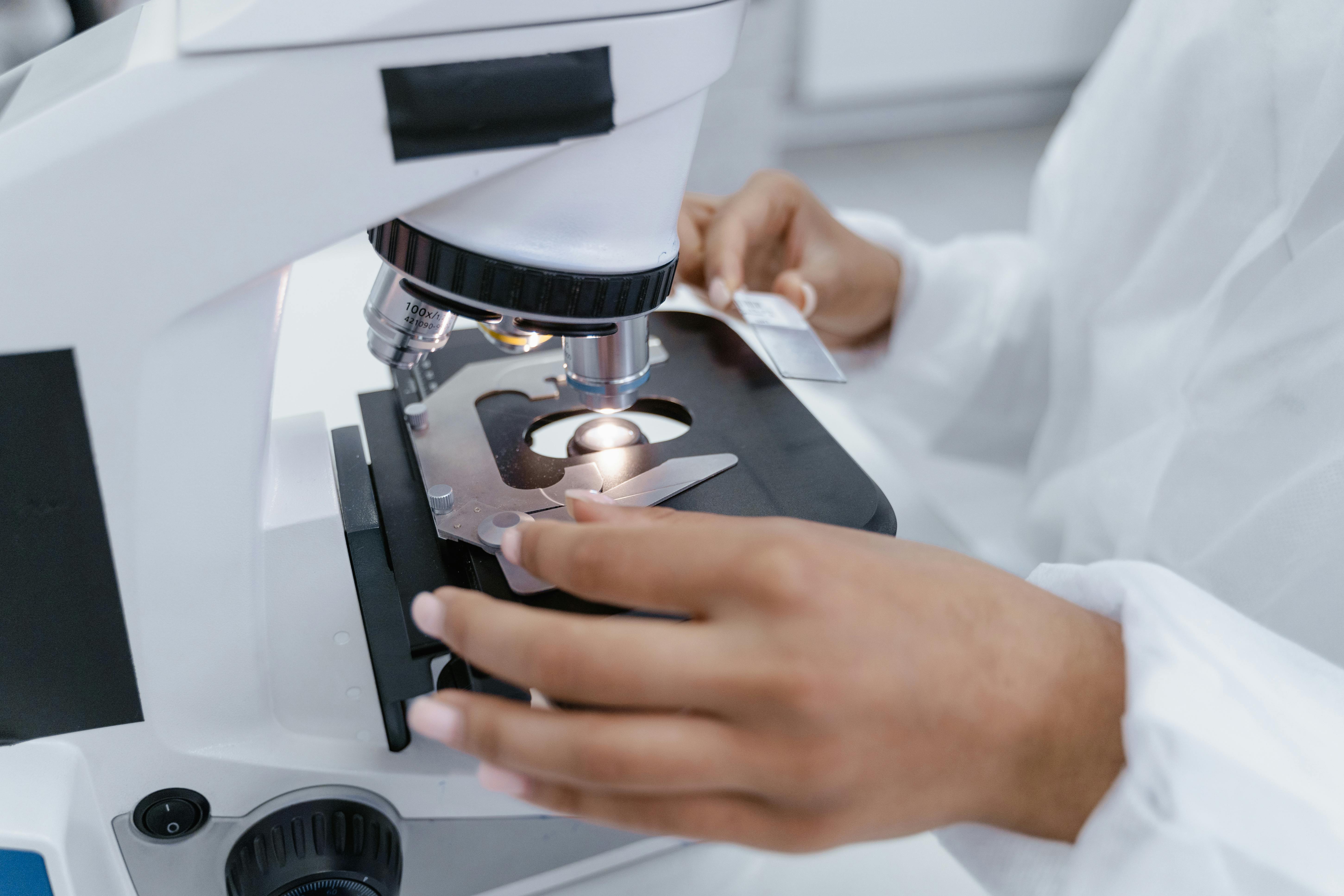 A Person in White Robe using a Microscope