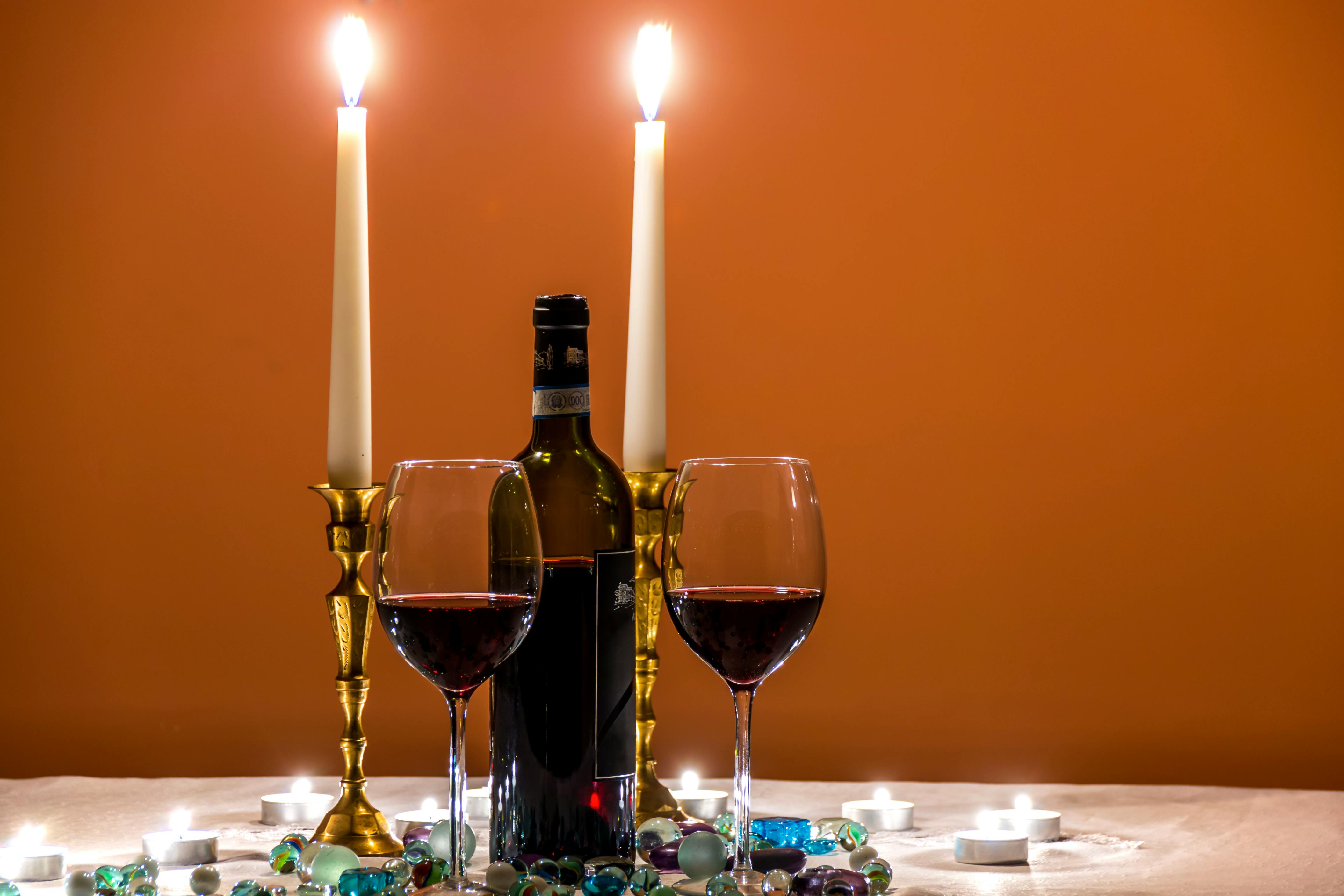 Two Almost Empty Long Stem Wine Glasses Beside Wine Bottle and Lighted Candles