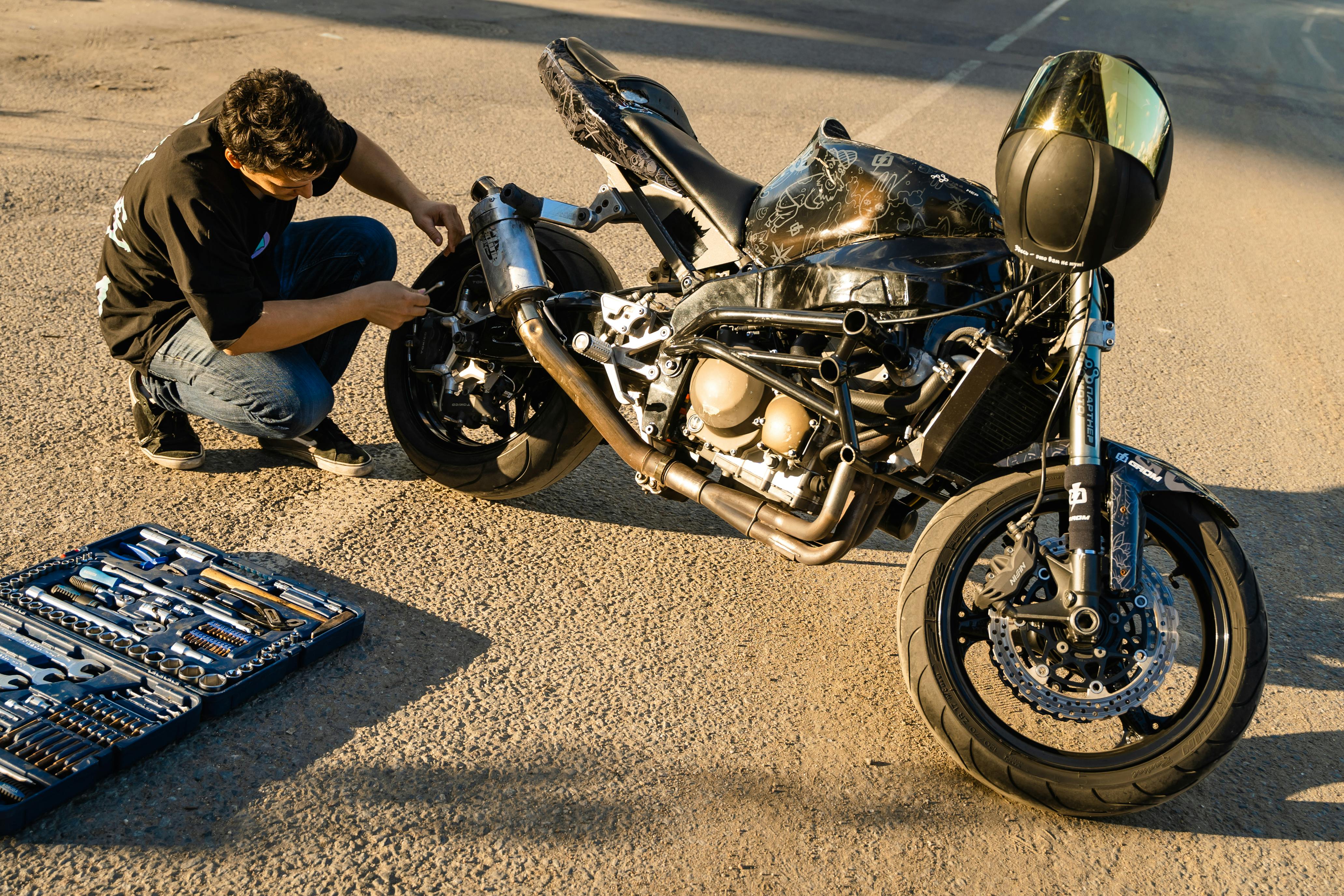 Man Fixing a Black Motorcycle