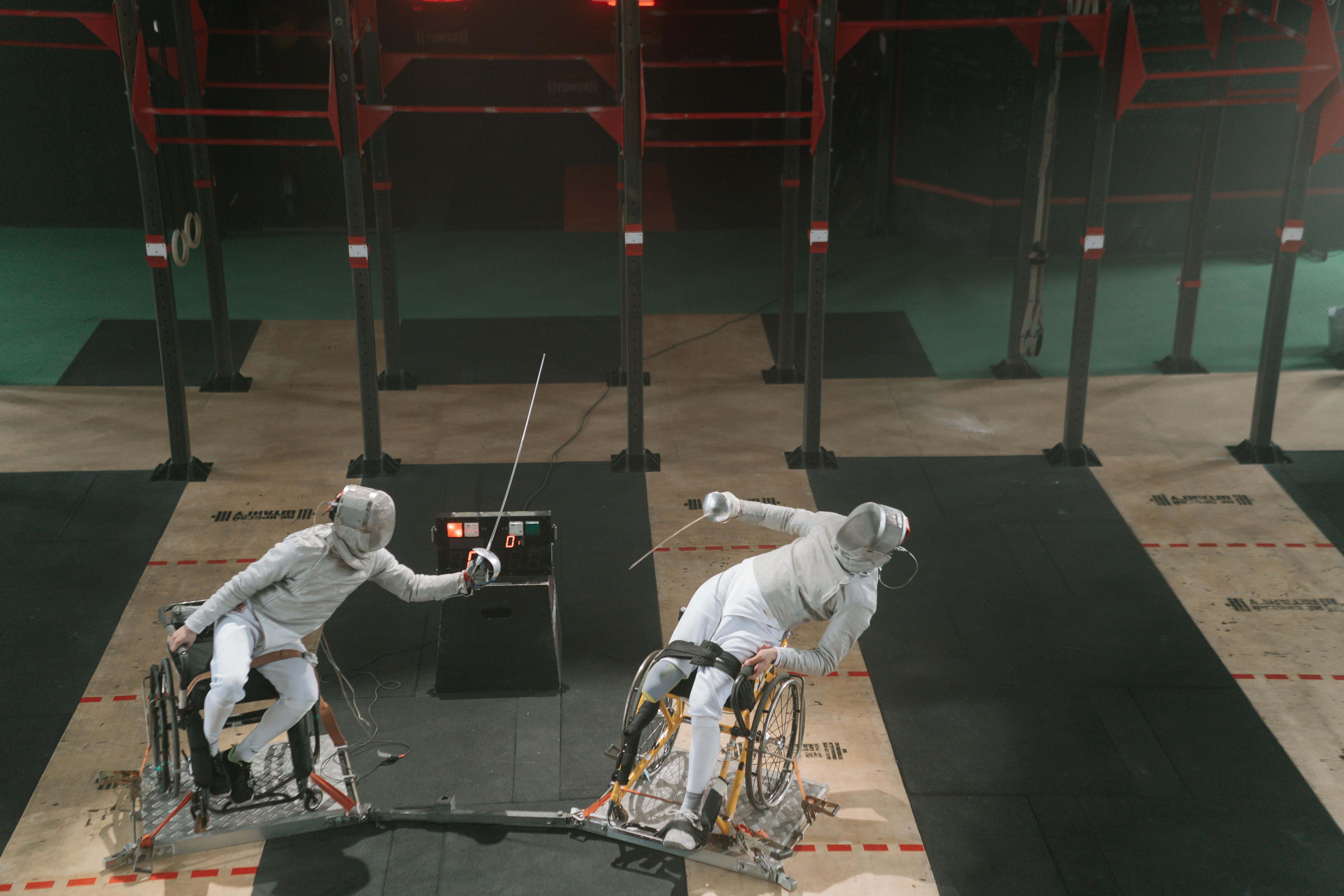 Two paralympic athletes fencing while wearing fencing sportswear