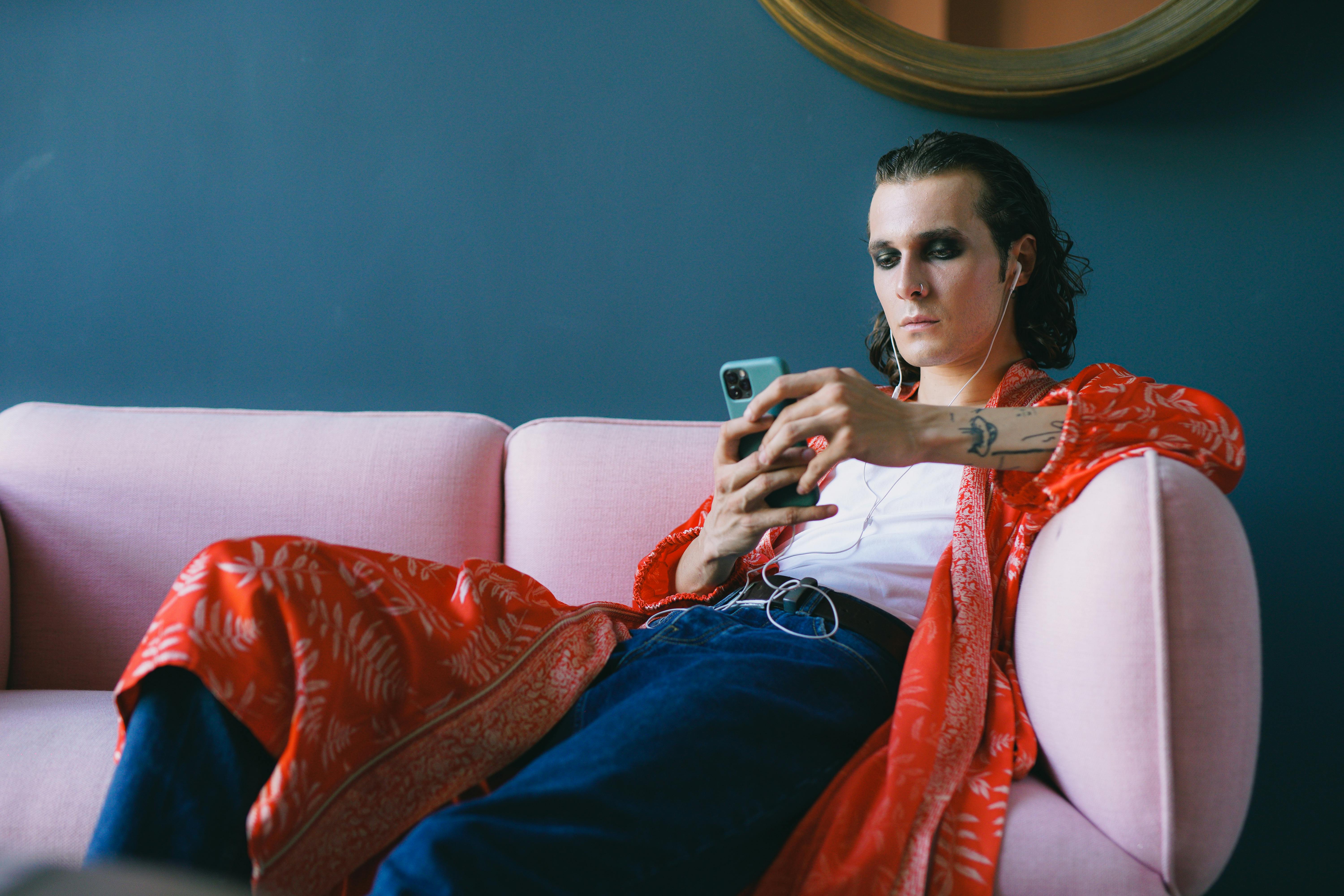 Man in red robe lounging on pink couch