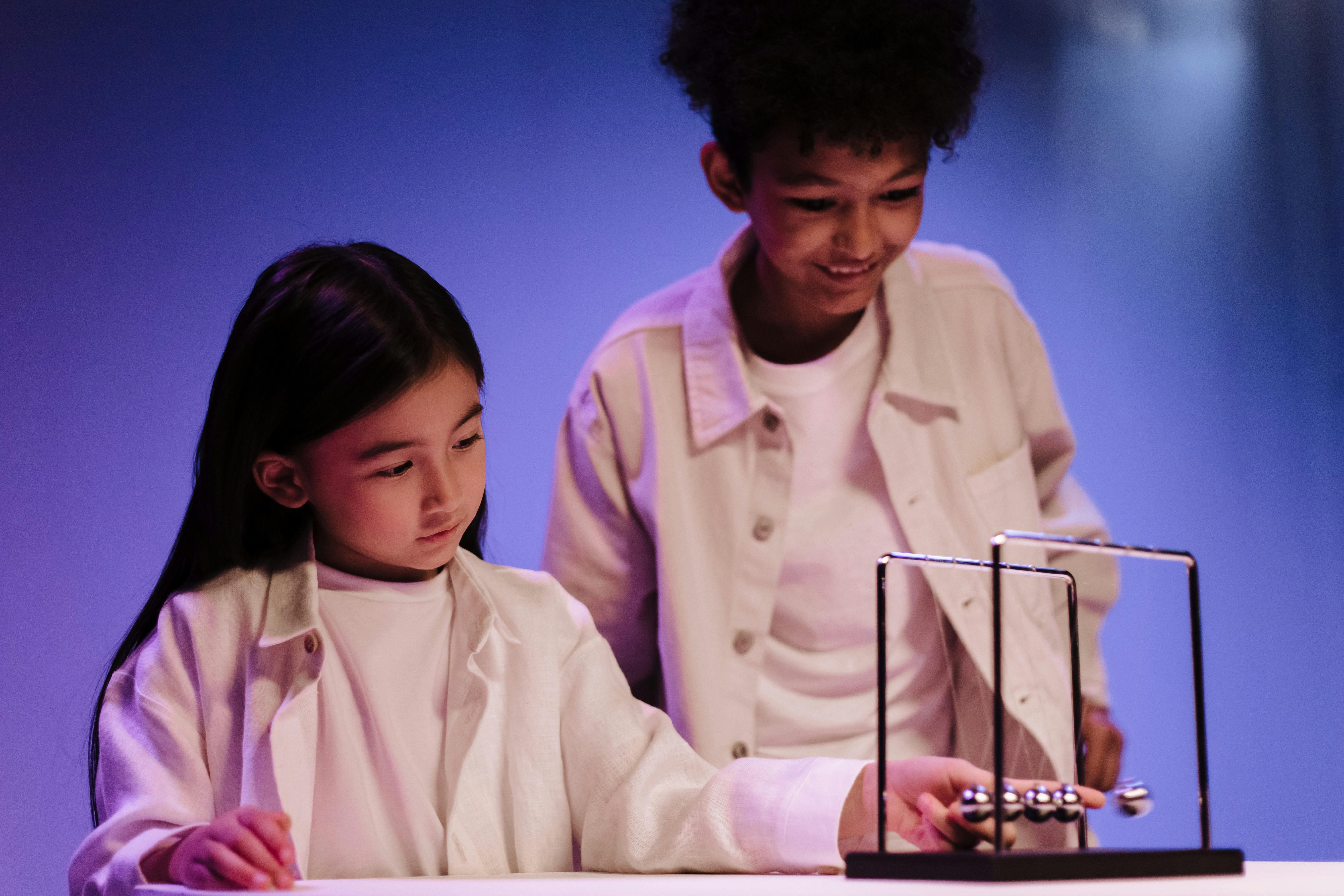 Boy and girl moving ball of newton s cradle