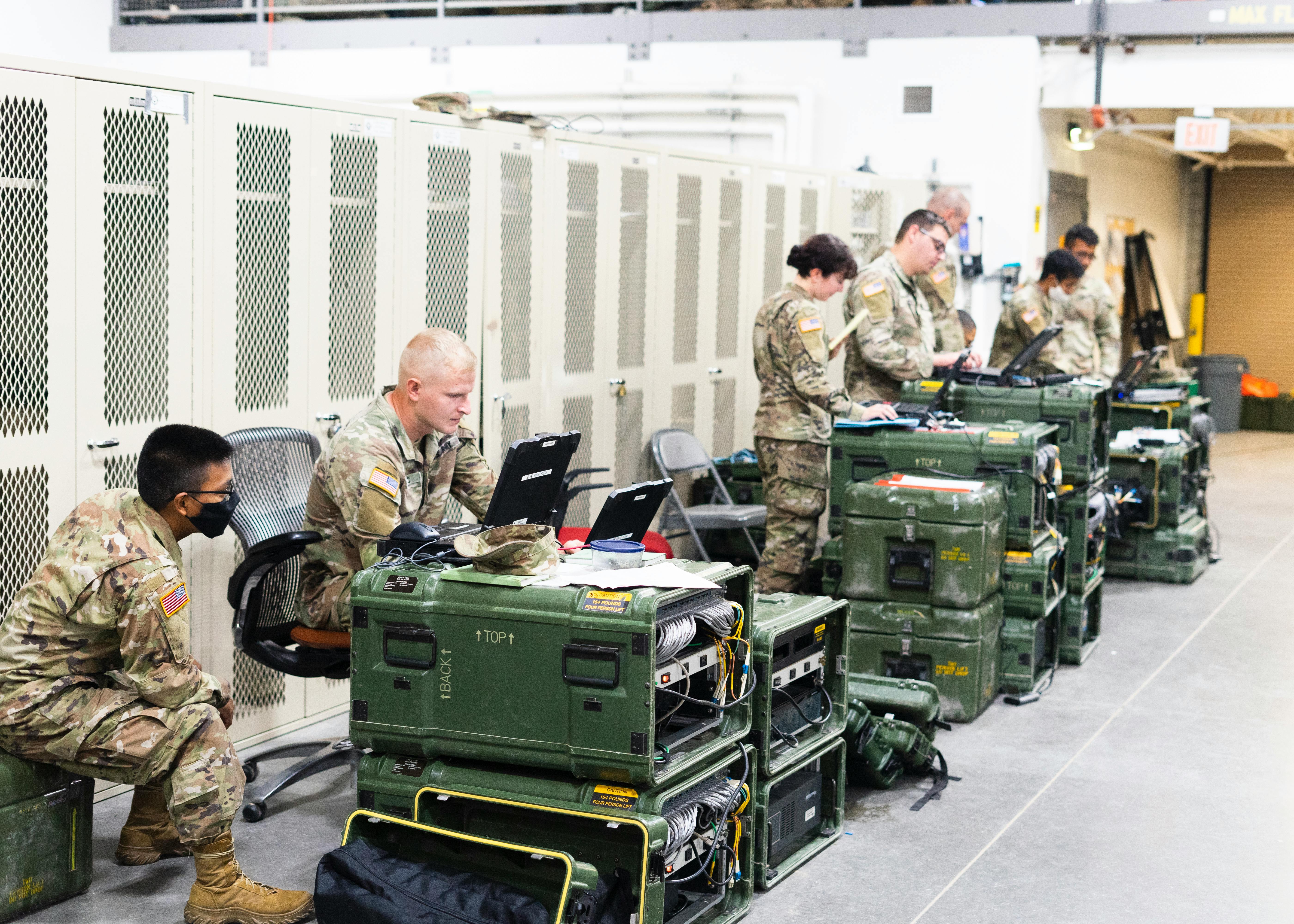 Soldiers Sitting beside Containers and Using Computers