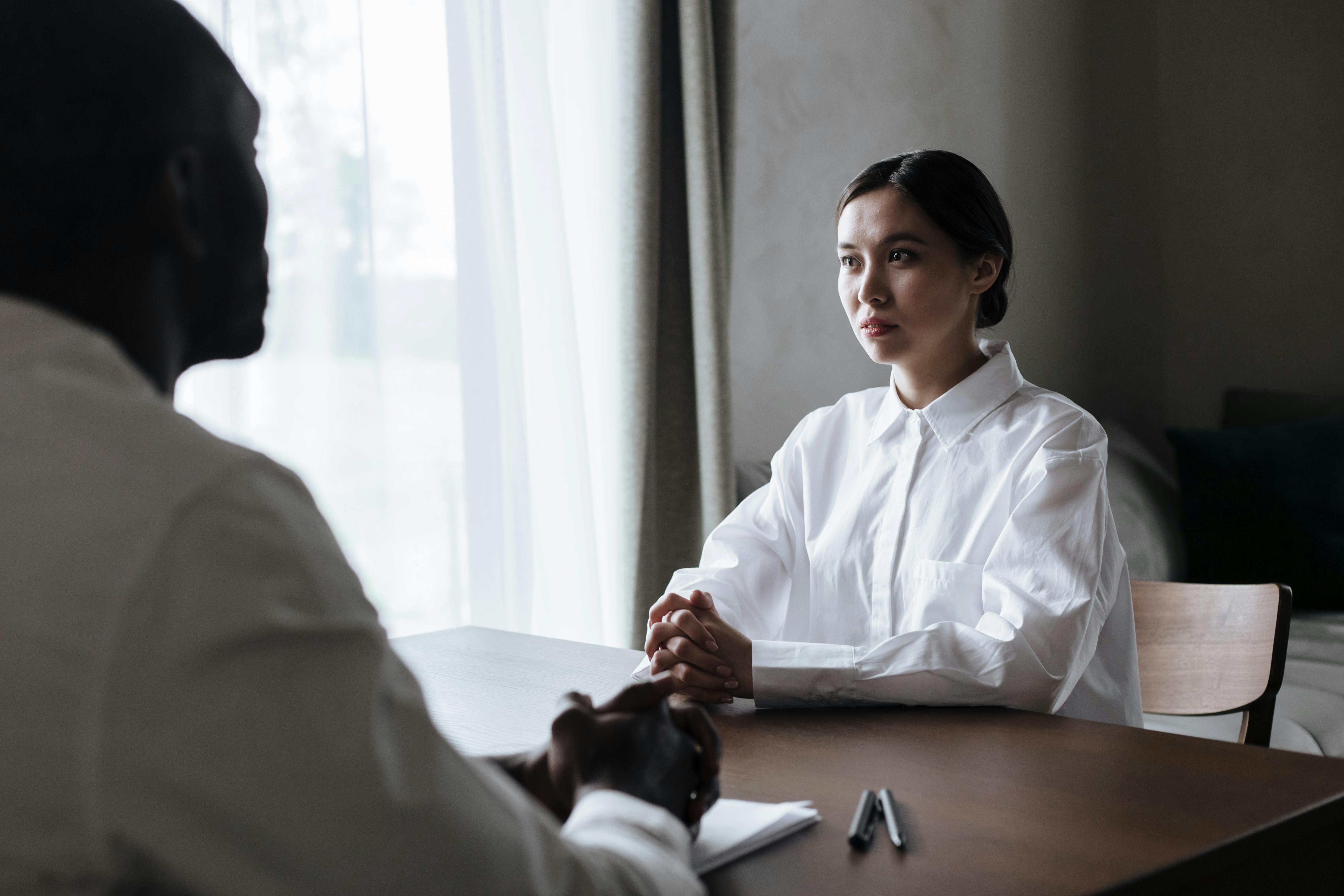 Man and Woman Sitting on Opposite Sides of Desk