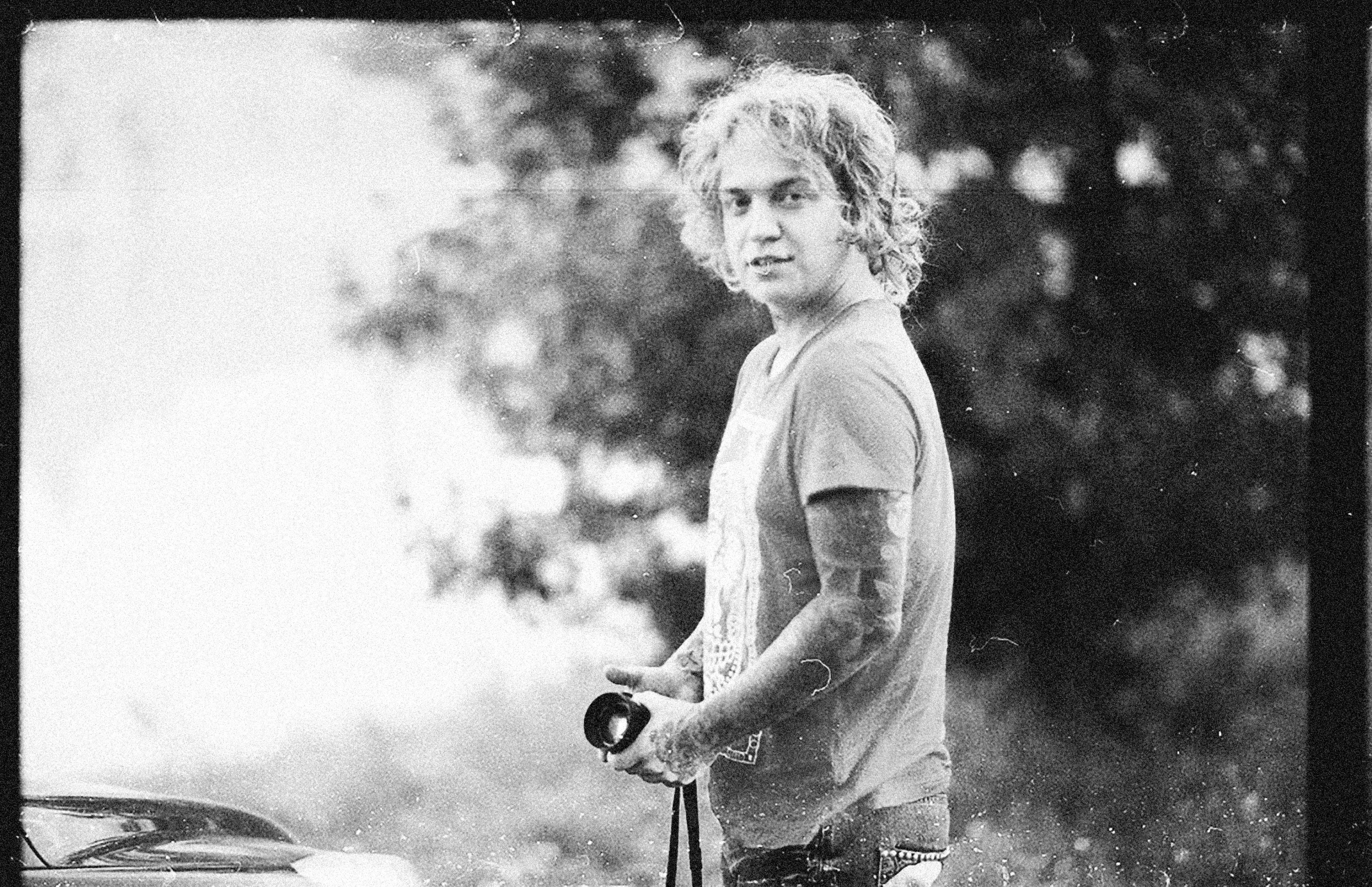 Blond Man with Tattoo on Arm Standing with Photo Camera in Hands
