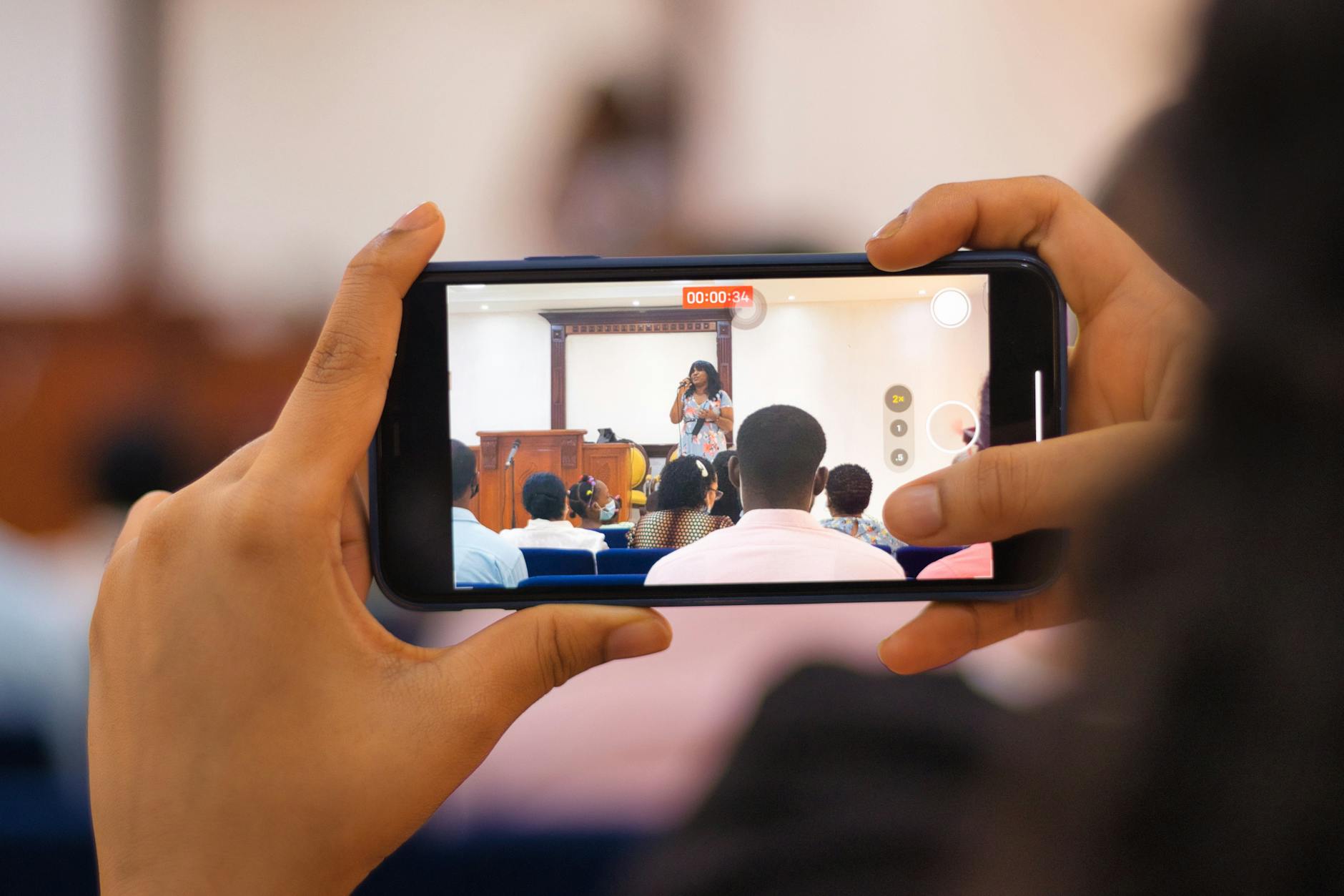 A Person Taking a Video of a Woman Singing on the Stage