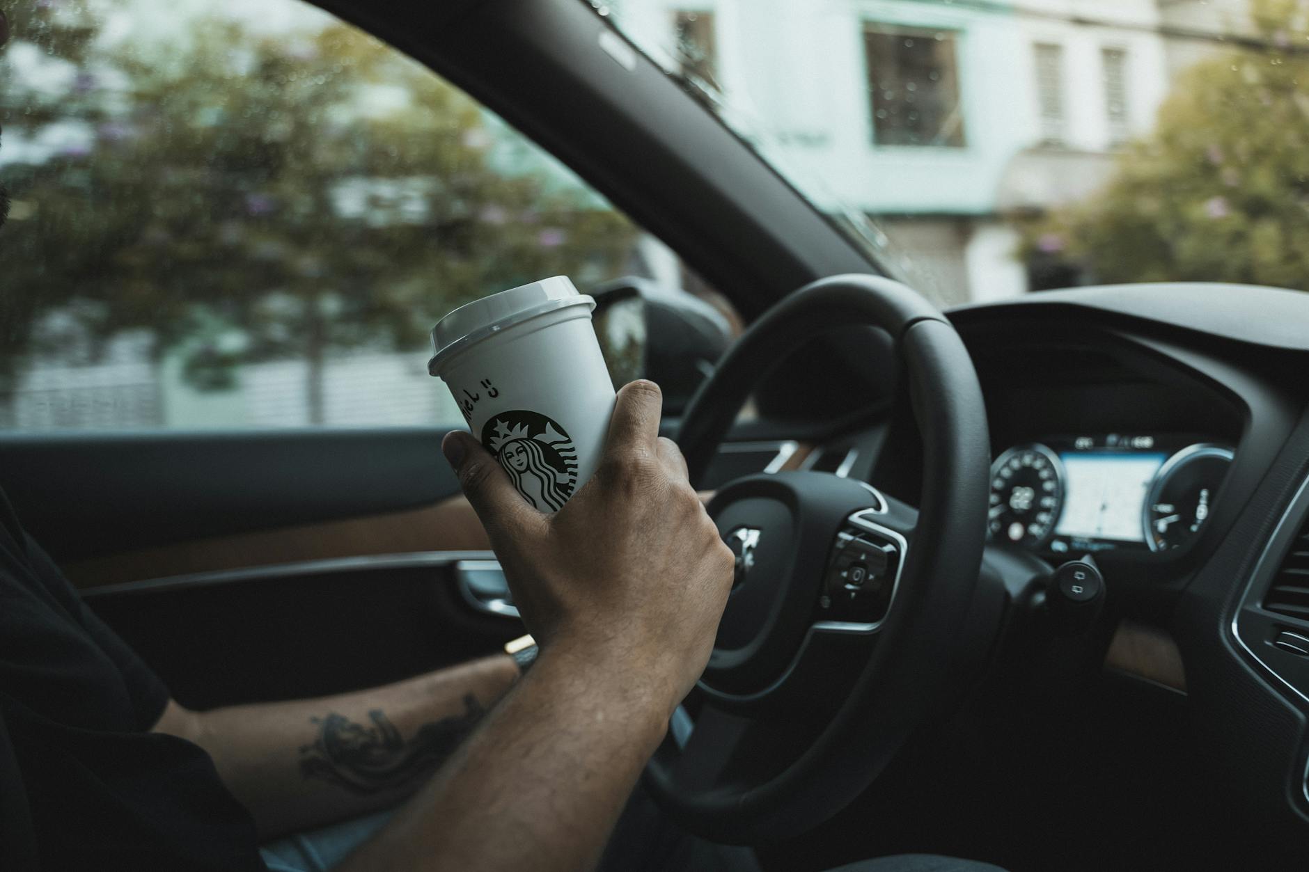 A Person Holding a Cup of Beverage While Sitting Inside a Car