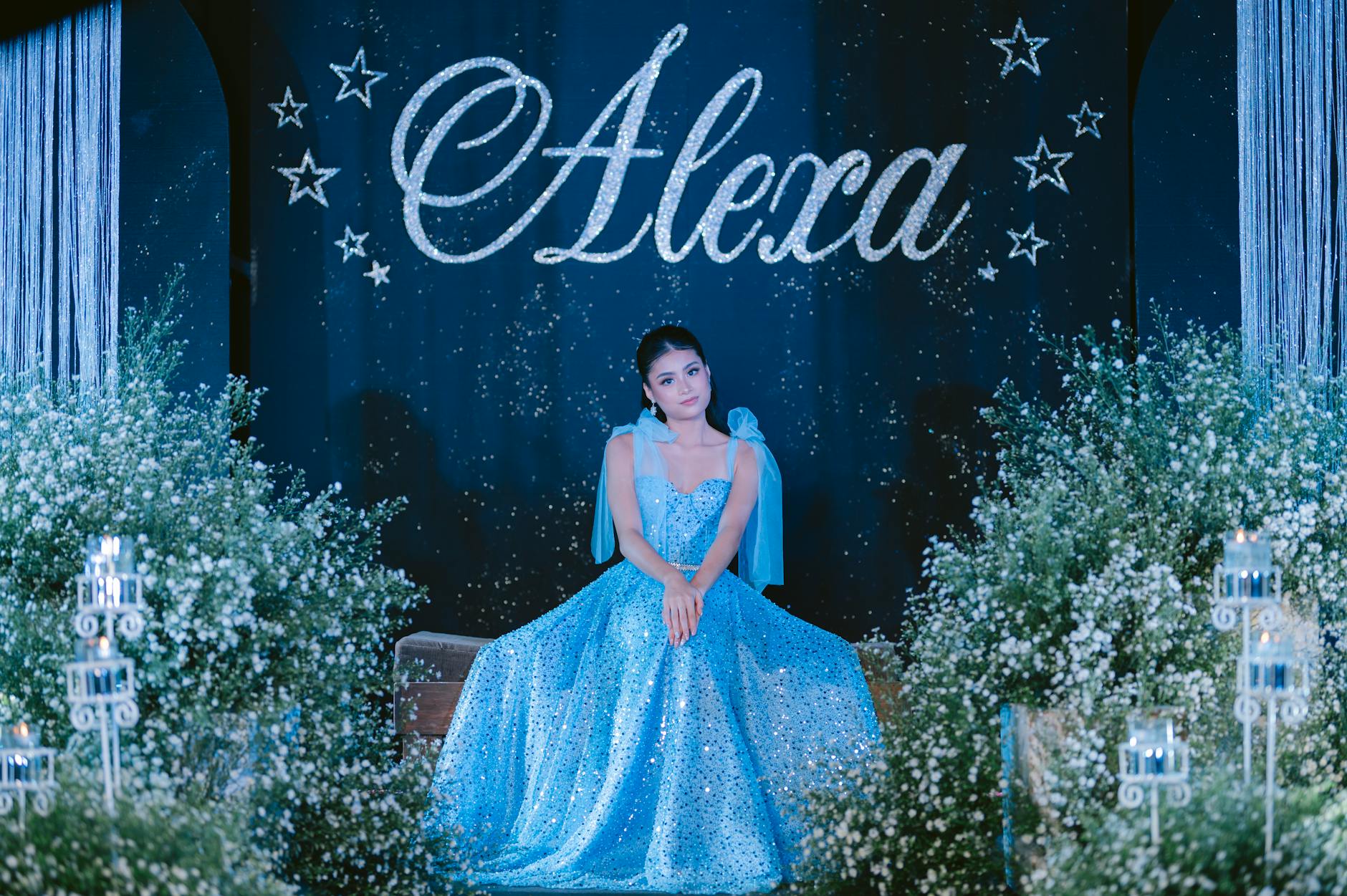 A Woman in Shiny Blue Dress Sitting on a Bench while Posing