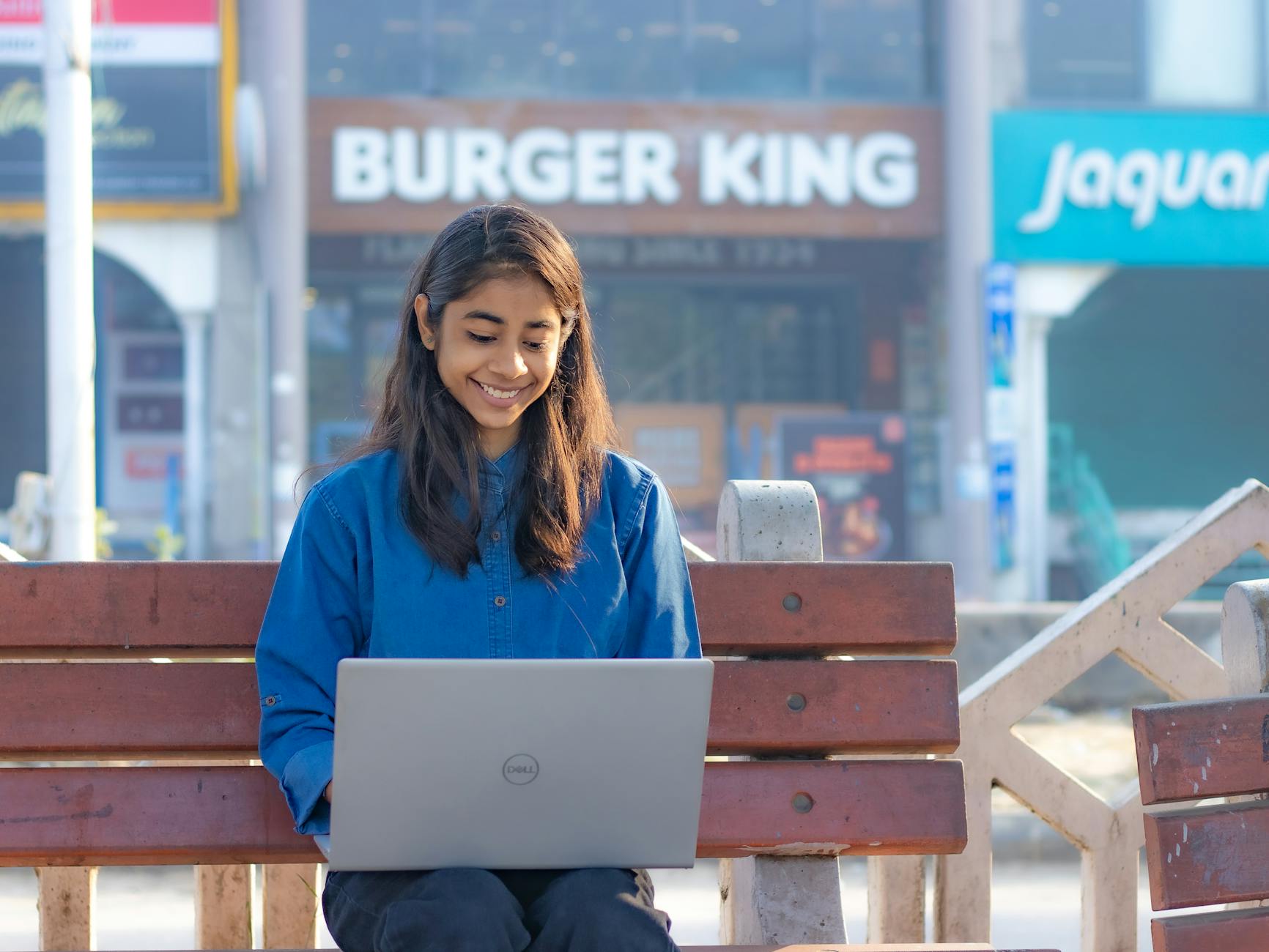 Pretty Woman in Blue Shirt Sitting on Bench with Laptop