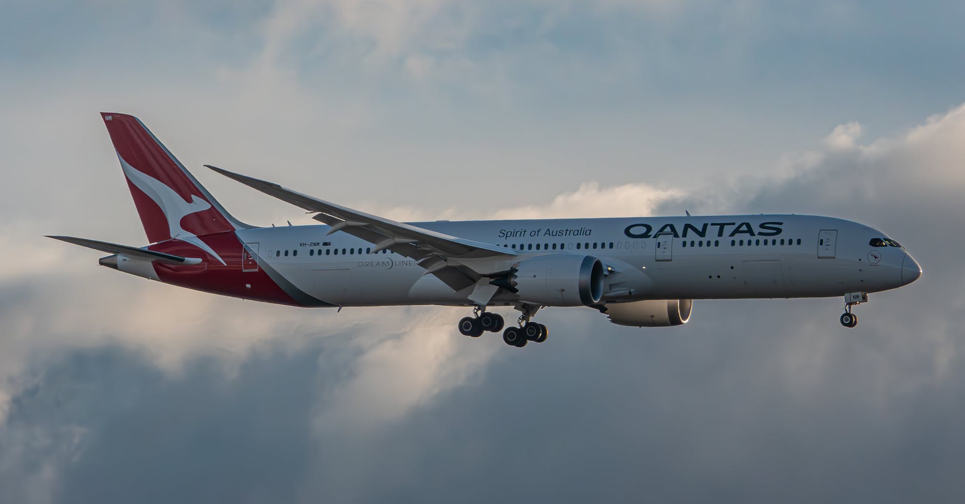 A Qantas Airliner Flying against a Cloudy Sky