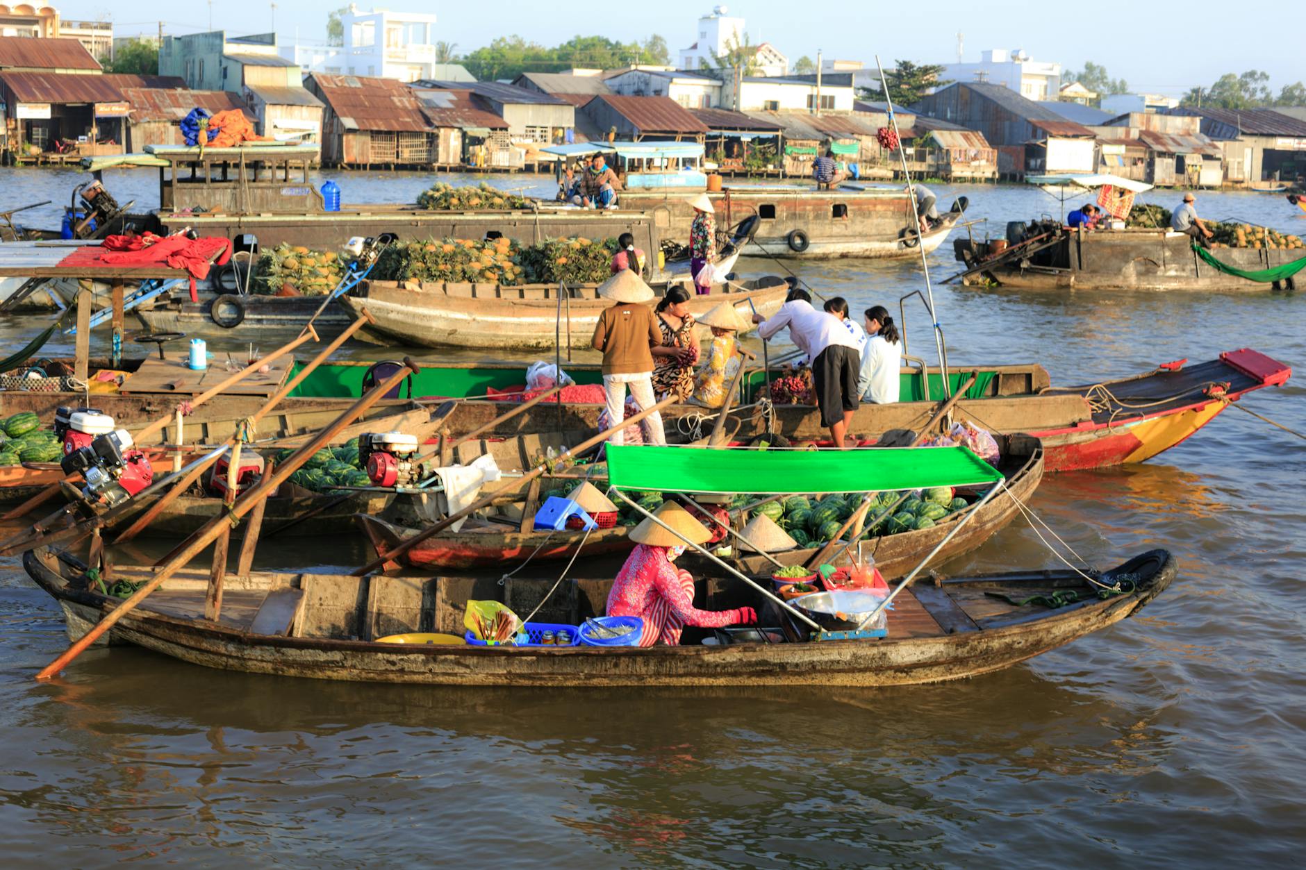 People Sitting and Standing on Boats With Different Goods on Display Near Houses